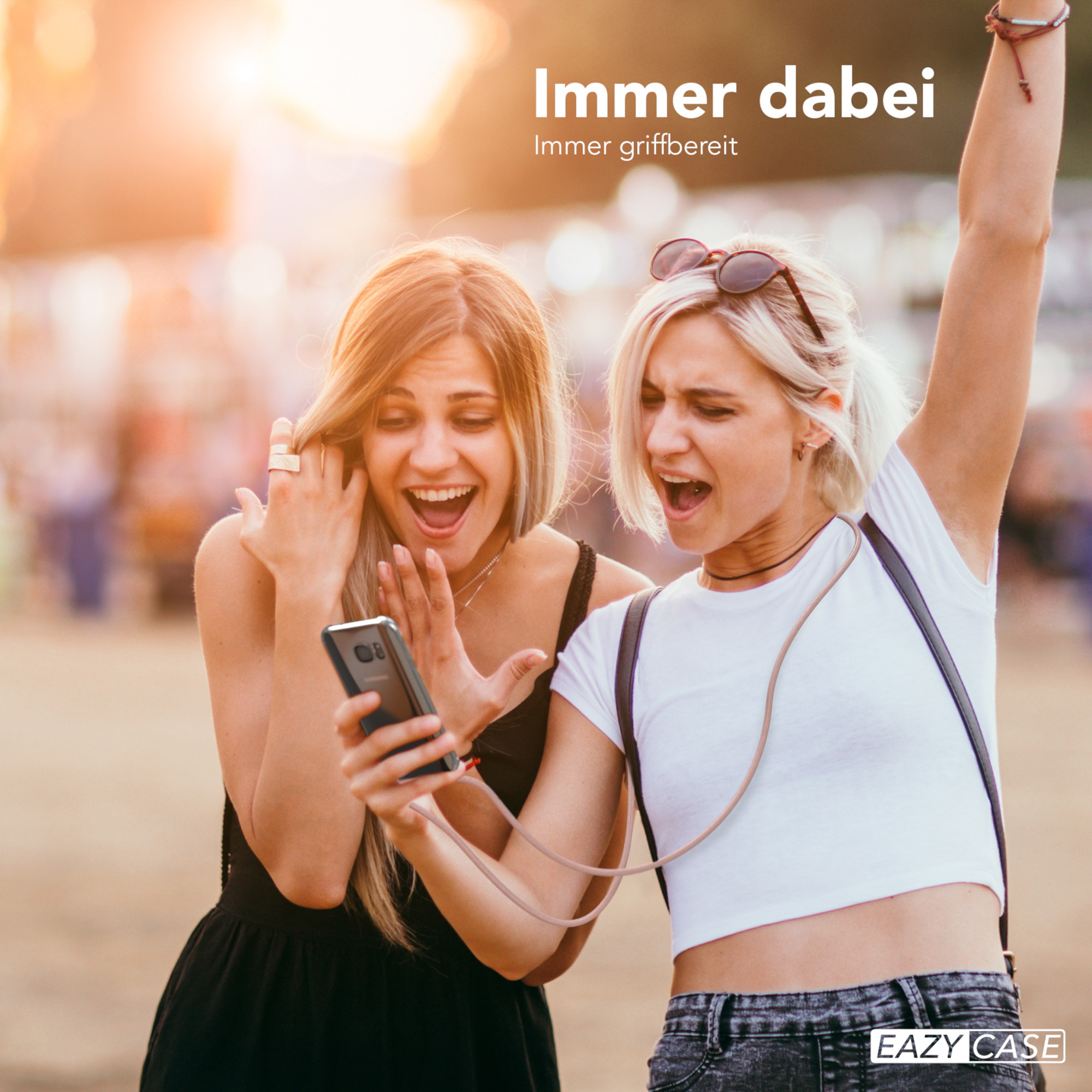 Zwei Frauen schauen auf ein Telefon, aufgeregt. Eine hält es, die andere hat Arme oben.