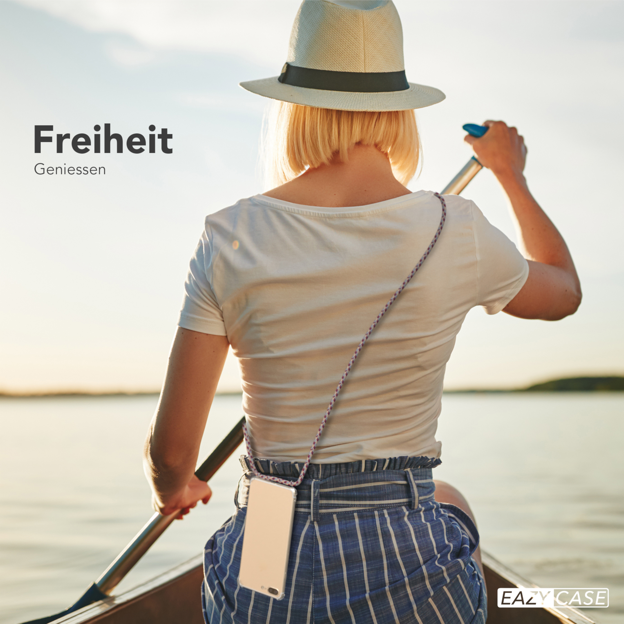 Frau paddelt bei Sonnenuntergang auf einem See, trägt einen Hut und hält ein Handy.