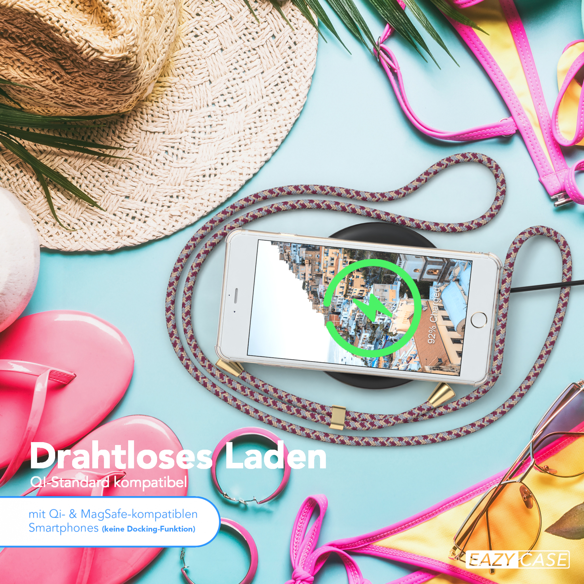Telefon auf kabellosem Ladegerät mit Seilhülle, Strandaccessoires drumherum.