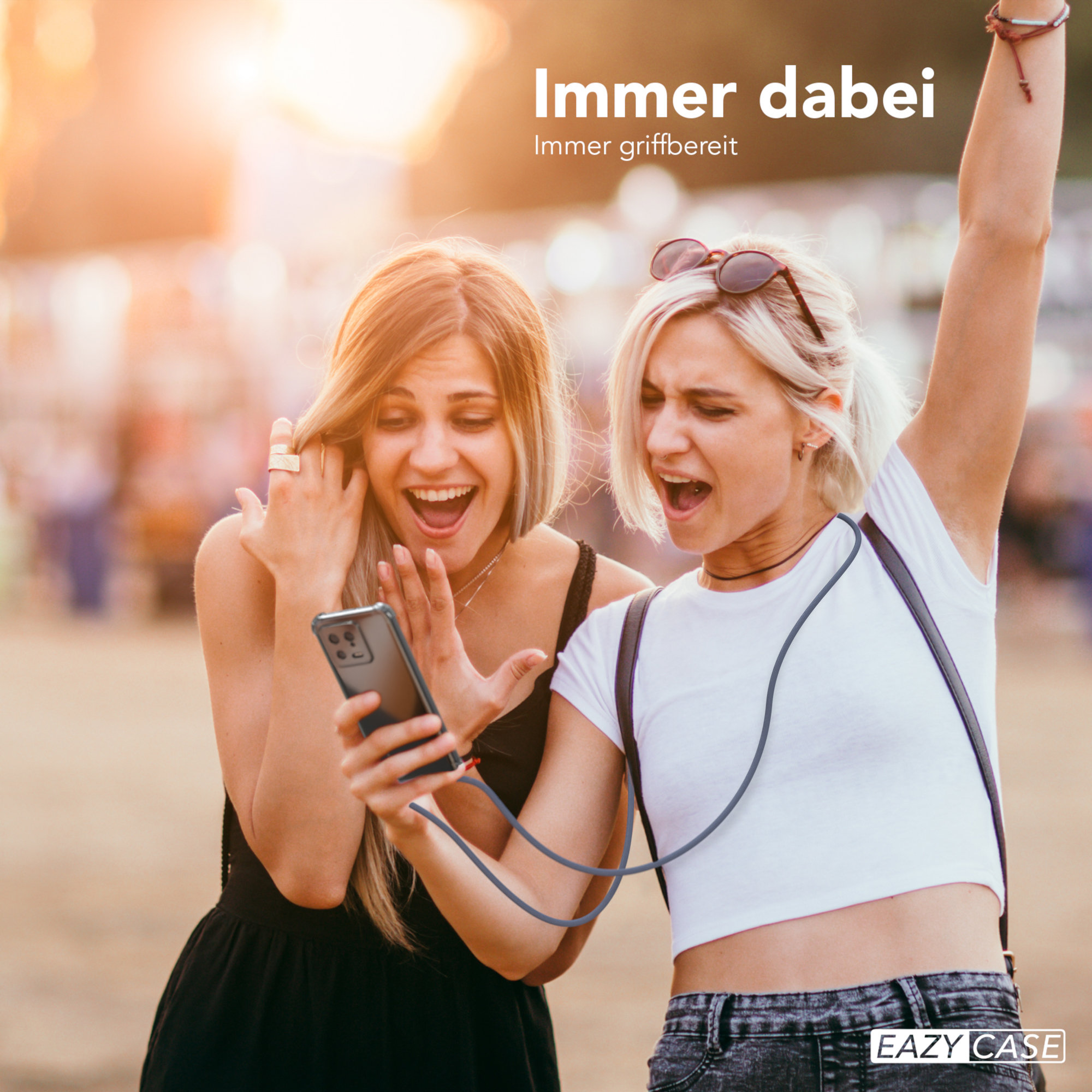 Zwei aufgeregte Frauen, die sich ein Telefon mit Hülle ansehen. Text: Immer dabei.