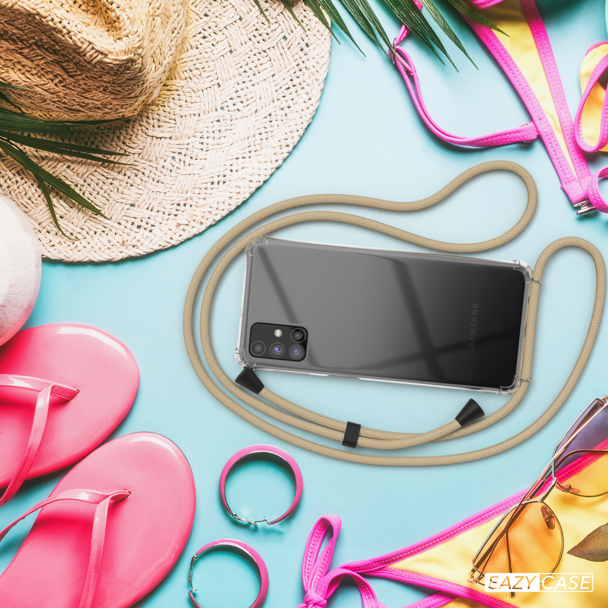 Ein Telefon mit beigem Kabel und Hülle liegt auf einem Tisch mit Strandaccessoires, darunter Hut, Sonnenbrille und rosa Artikel.