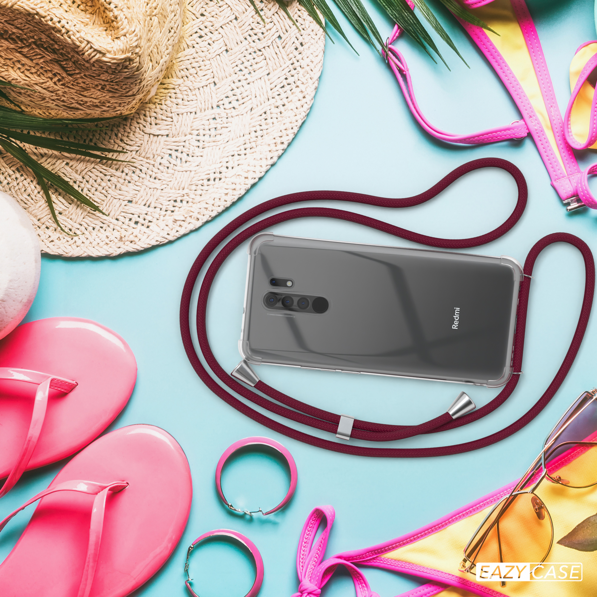 Telefon mit Lanyard am Strand. Rotes Lanyard, pinke Flip-Flops, Sonnenbrille und Strohhut.