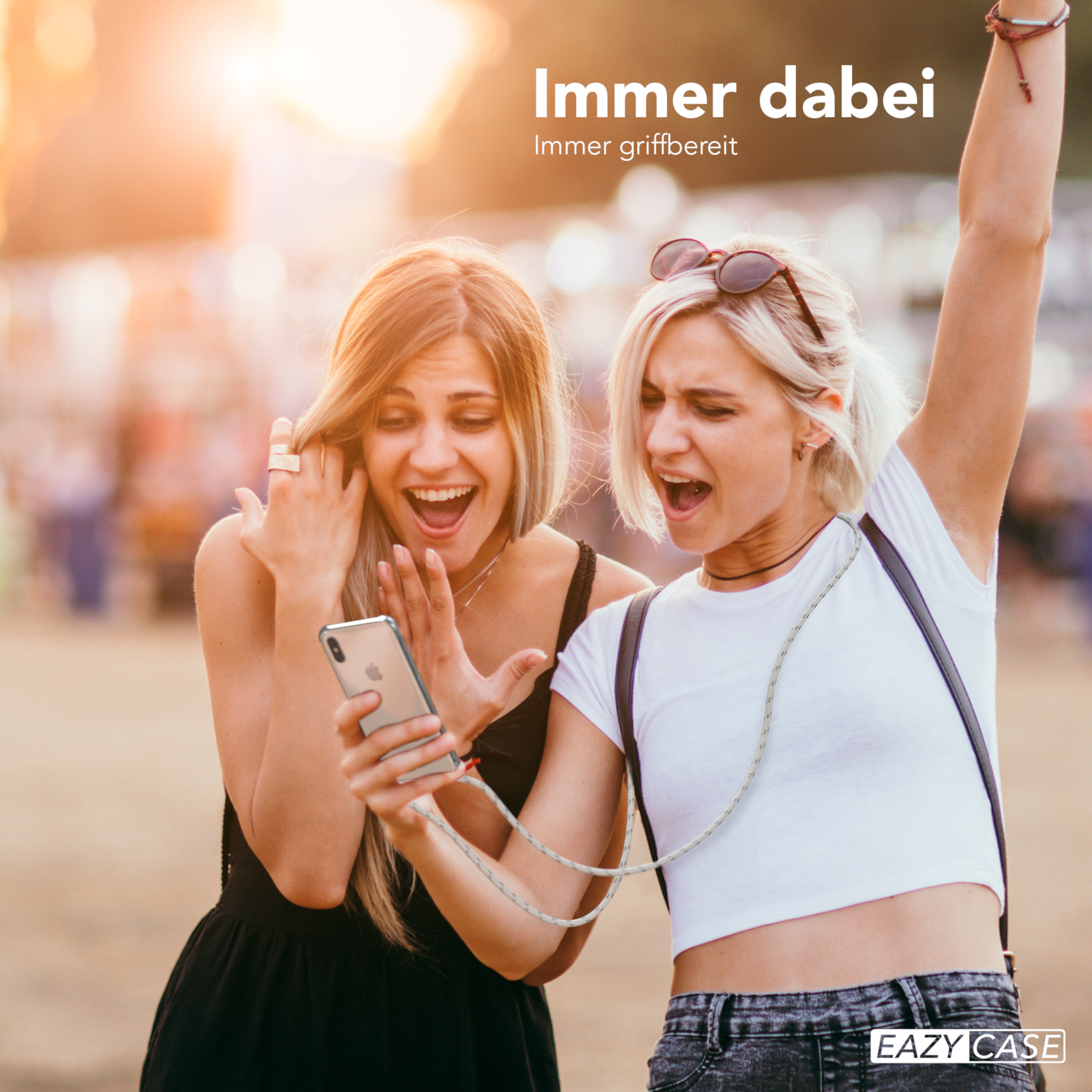 Zwei Frauen schauen auf Telefon mit Gurt. Text: Immer dabei, Immer griffbereit.
