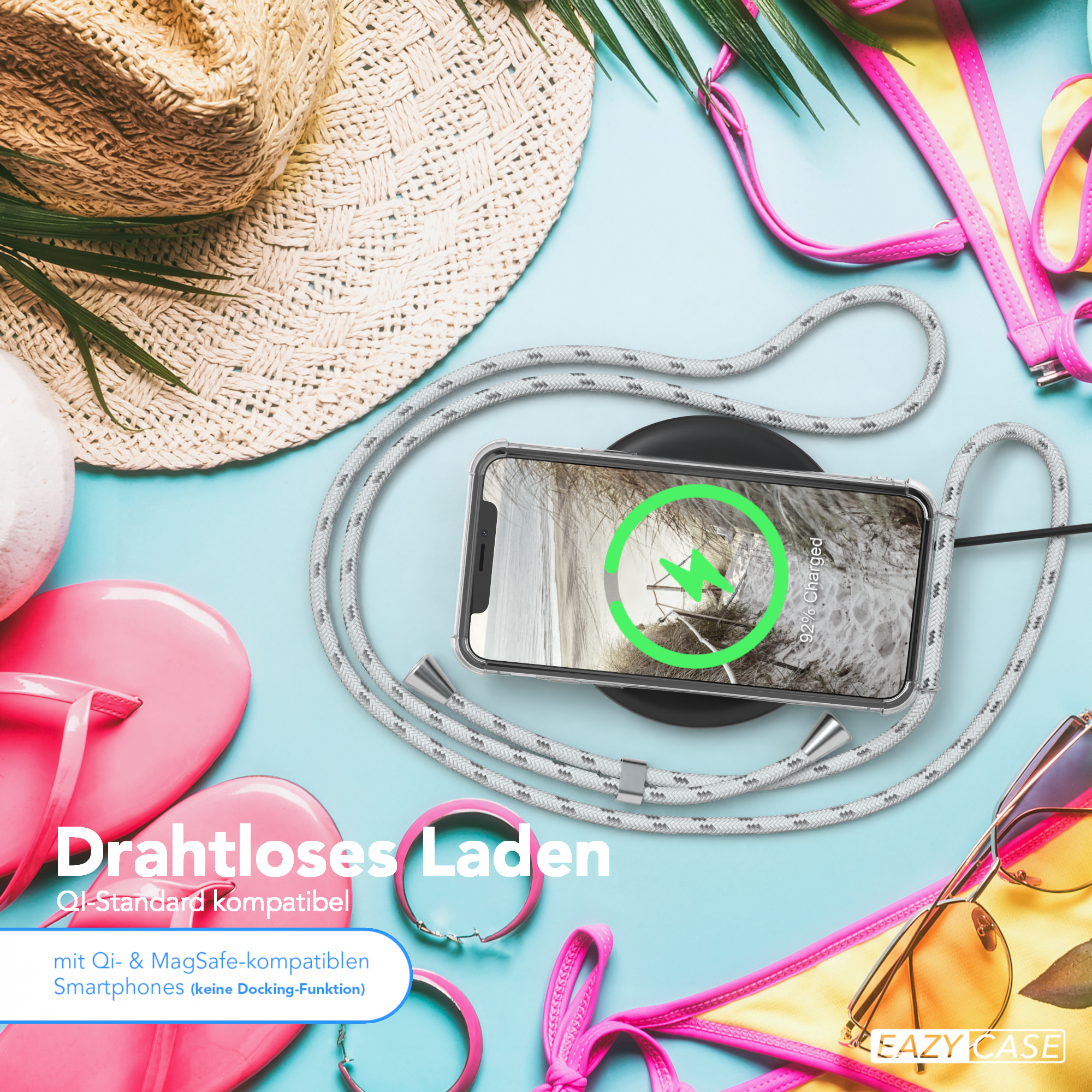 Ein Telefon auf einem Ladegerät mit einem Kabel darum. Strandaccessoires sind drumherum.