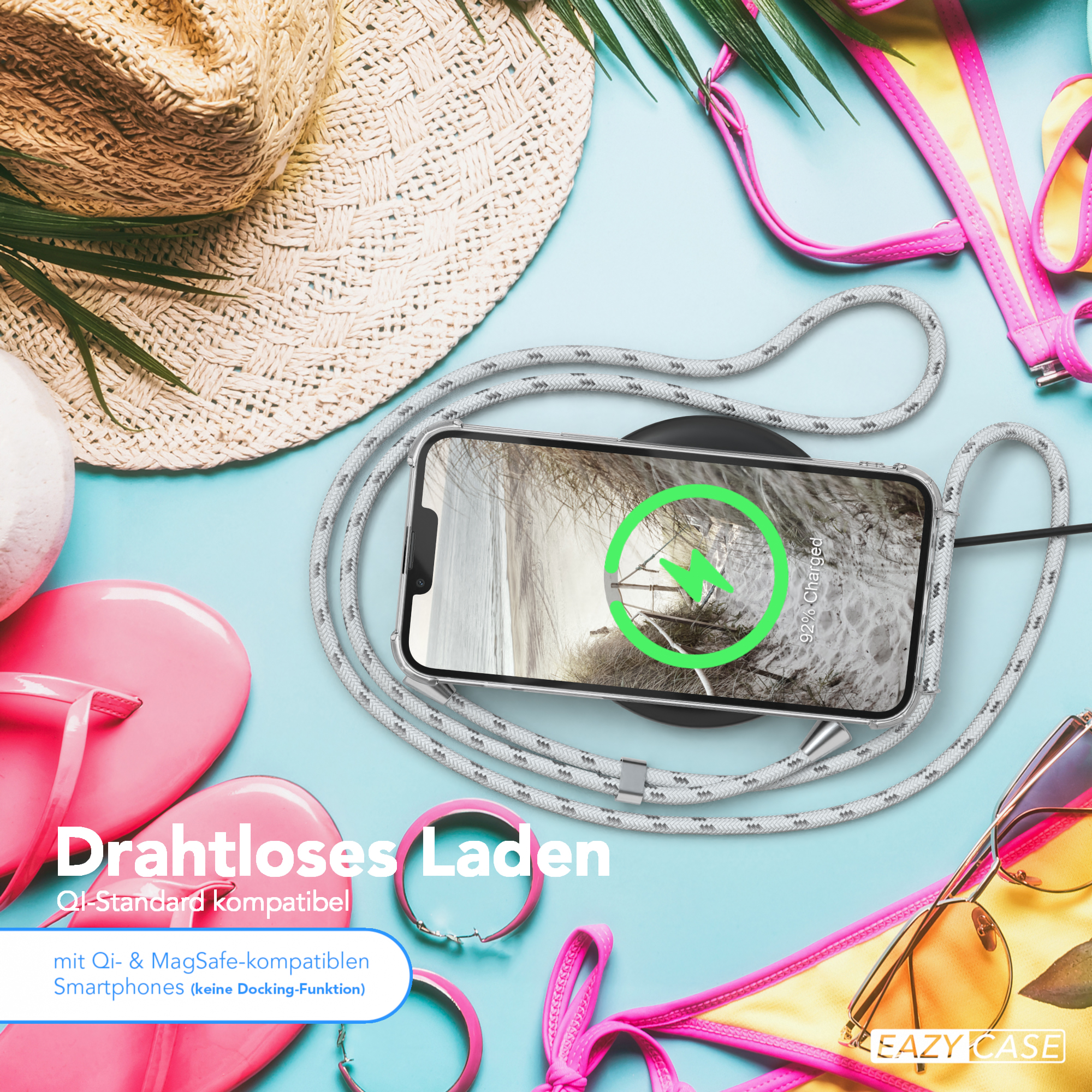 Telefon wird drahtlos geladen. Strandaccessoires im Hintergrund.