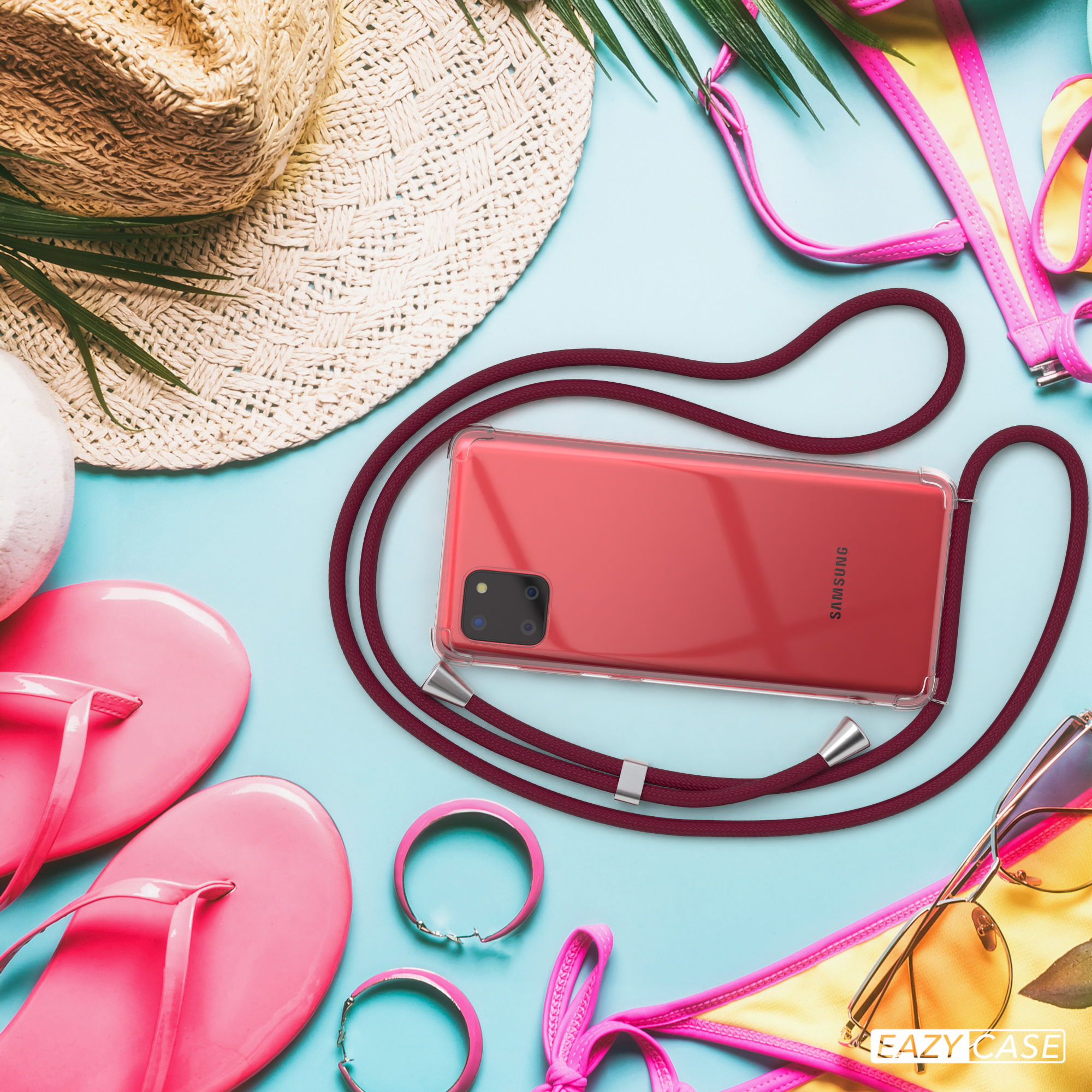 Strandszene mit Handyhülle, Sonnenbrille, Hut, rosa Flip-Flops und Bikini. Blauer Hintergrund.