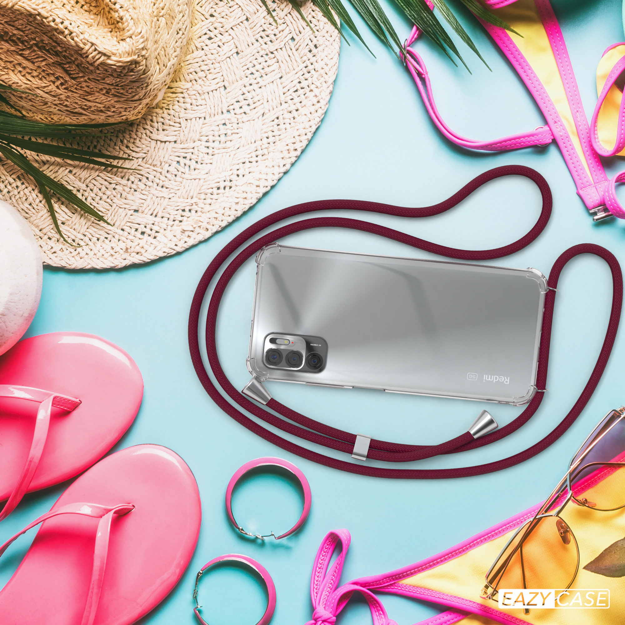 Telefon mit Hülle, Hut, Sonnenbrille, rosa Armbändern und Flip-Flops auf blauem Grund.