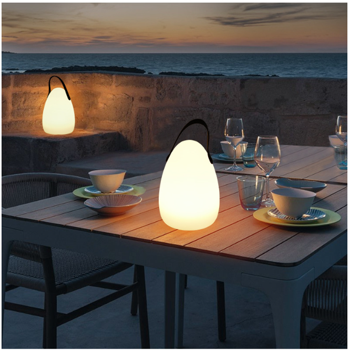 Zwei leuchtende eiförmige Lichter auf einem Tisch. Auf dem Tisch stehen Gläser, Teller und Wassergläser.
