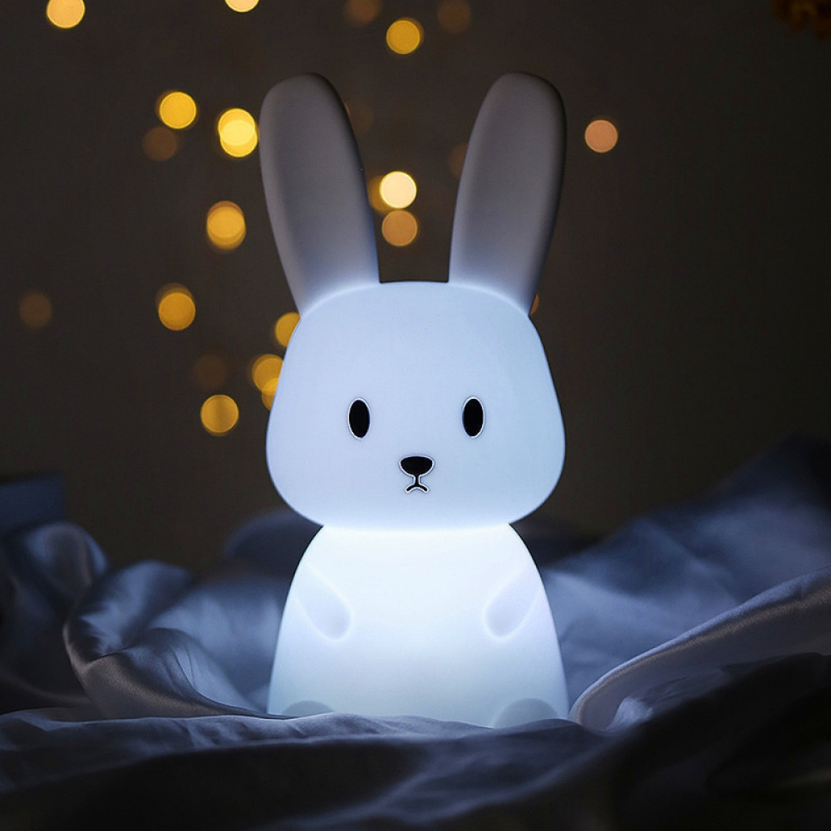 Weißes Hasen-Nachtlicht, mit verschwommenen Lichtern im Hintergrund, auf Satin.