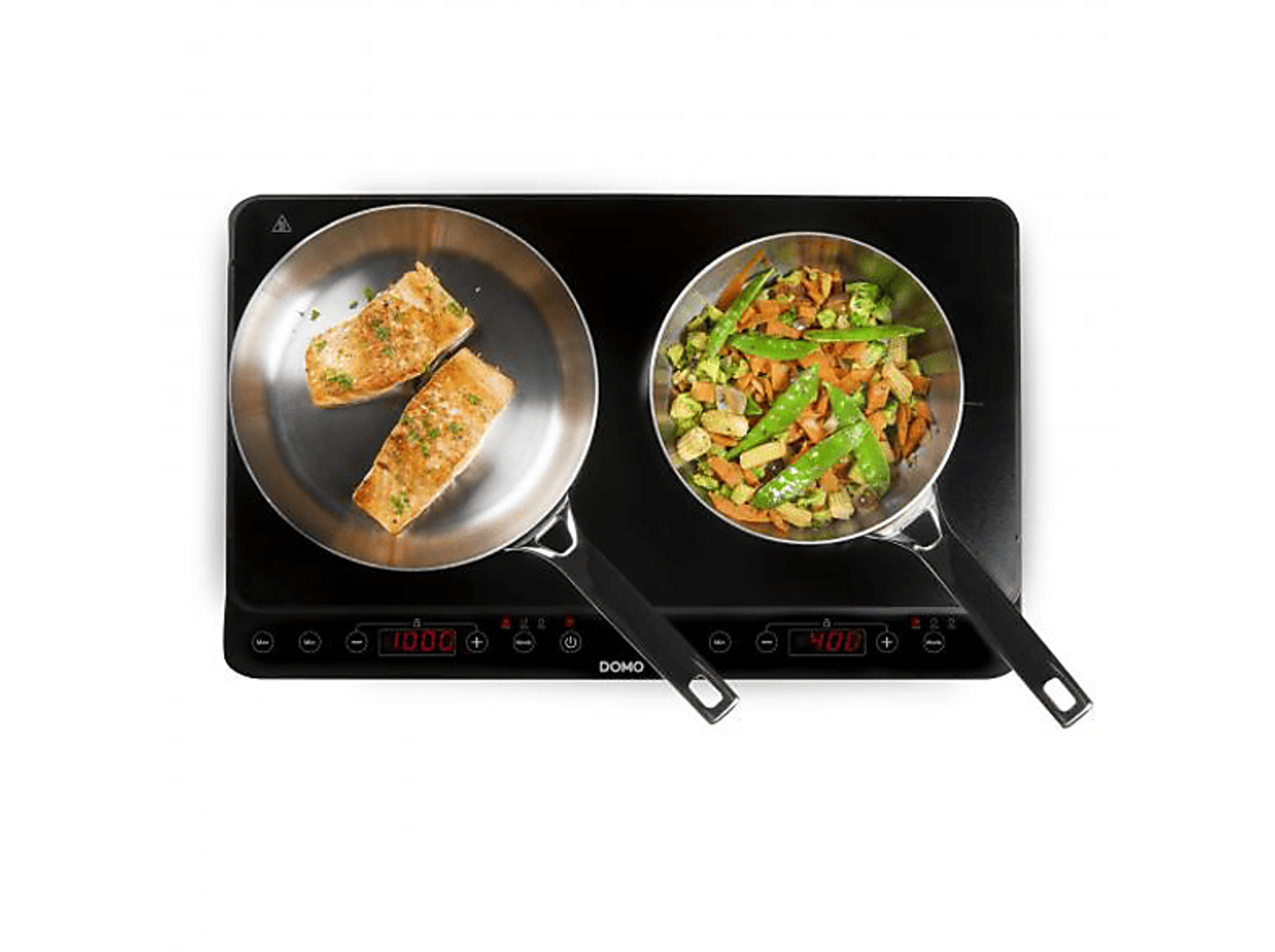 Dwie patelnie na czarnej płycie grzewczej. Jedna z rybą, druga z warzywami.