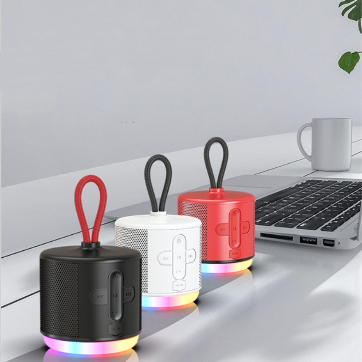 Drei bunte Lautsprecher auf einem Tisch. Einer rot, einer weiß und einer schwarz mit Regenbogenlichtern.