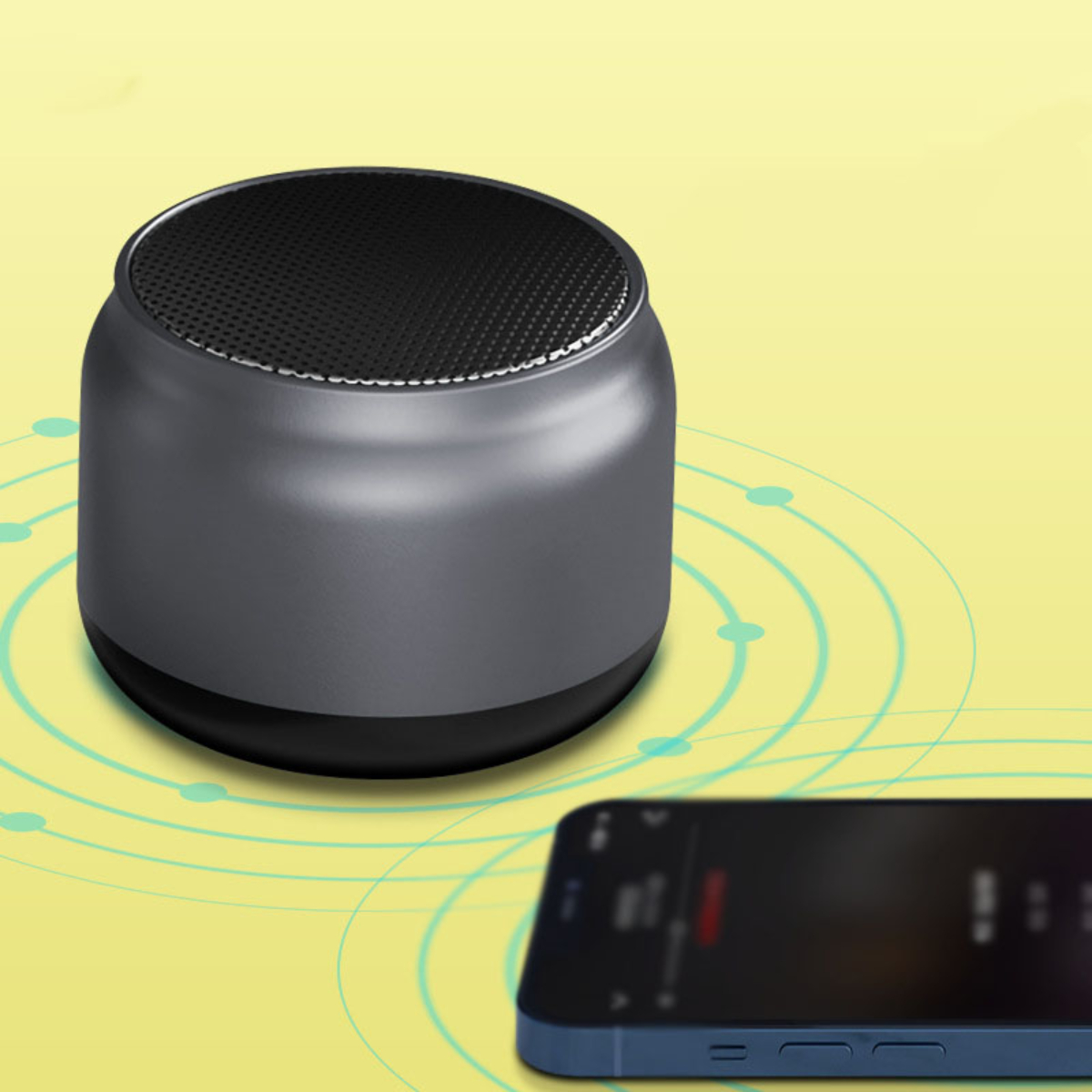 Ein grauer Mini-Lautsprecher neben einem Smartphone, das Musik auf gelbem Hintergrund abspielt.