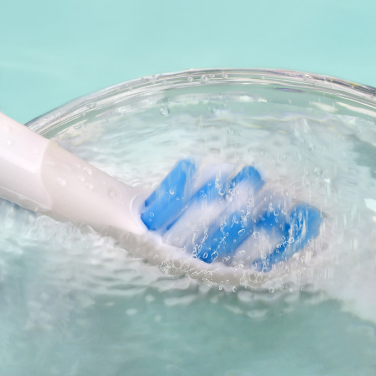 Ein Zahnbürstenkopf in einem Glas Wasser. Blaue Borsten sind sichtbar.