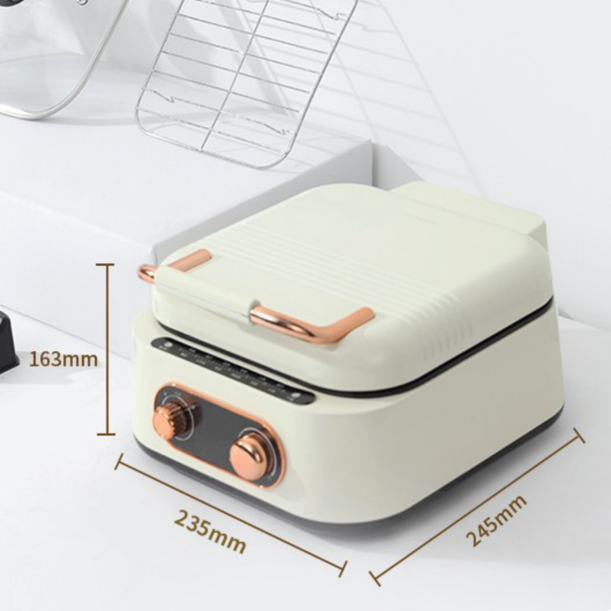Cremefarbener Sandwichmaker. Abmessungen sind angegeben. Ein Glasdeckel und ein Metallrost sind im Hintergrund sichtbar.