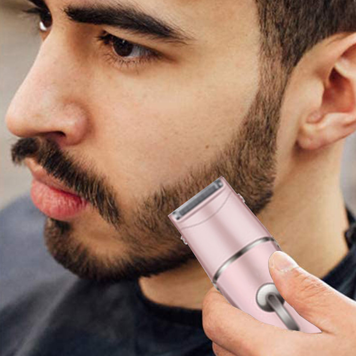 Ein Mann lässt sich seinen Bart mit einem rosa Trimmer trimmen. Das Gesicht des Mannes ist sichtbar.
