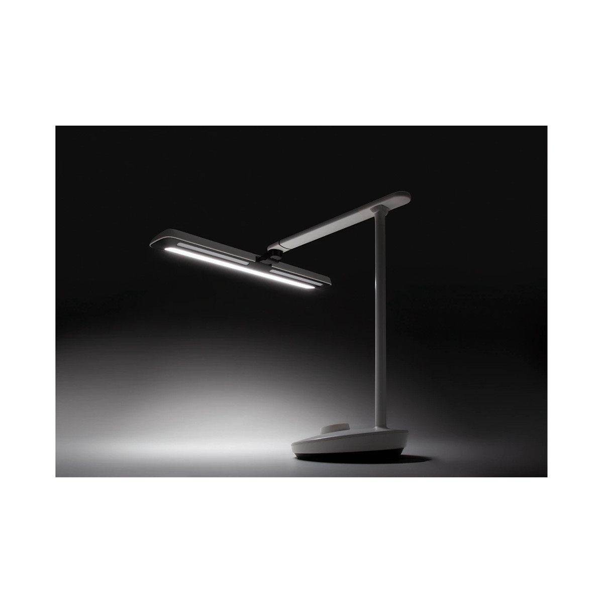 Una moderna lampada da scrivania bianca con luce intensa su sfondo scuro.