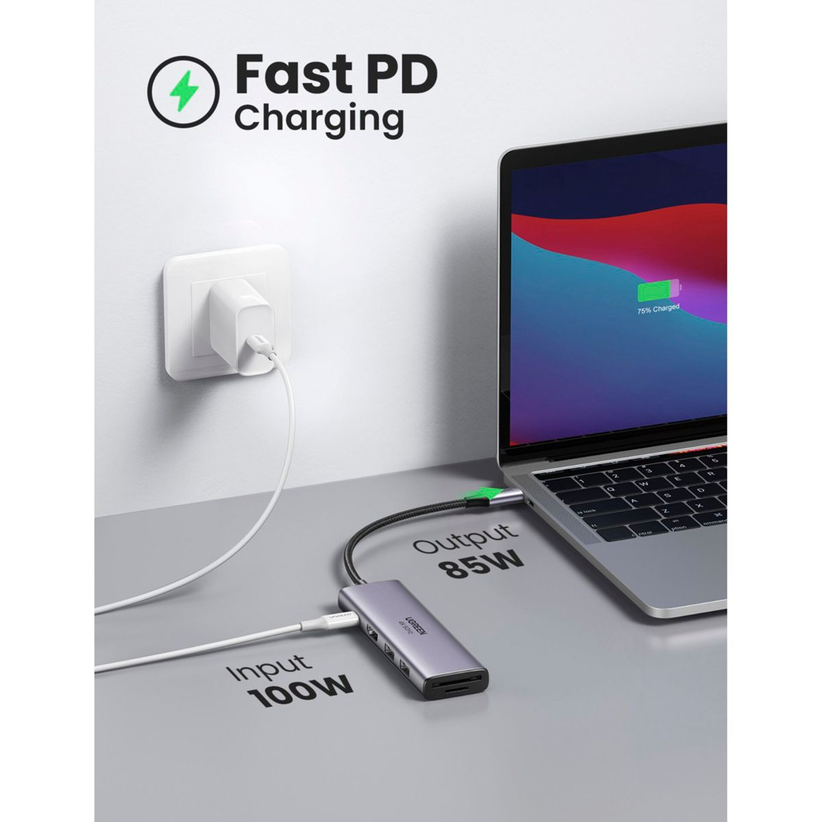 Laptop podłączony do koncentratora USB-C ładującego się przez adapter ścienny. Koncentrator jest oznaczony UGREEN.