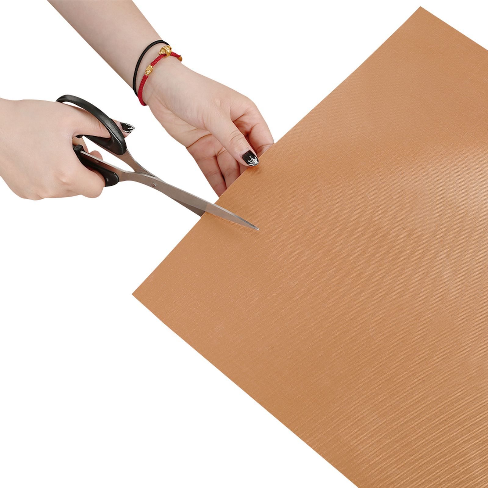 Eine Person schneidet ein braunes Blatt mit einer Schere. Die Schere ist schwarz mit silbernen Klingen.
