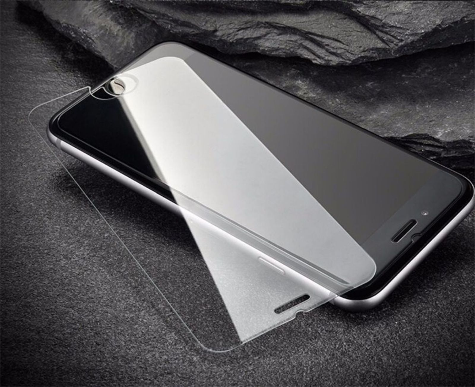 Telefon mit angebrachtem Displayschutz auf dunkler, strukturierter Oberfläche.