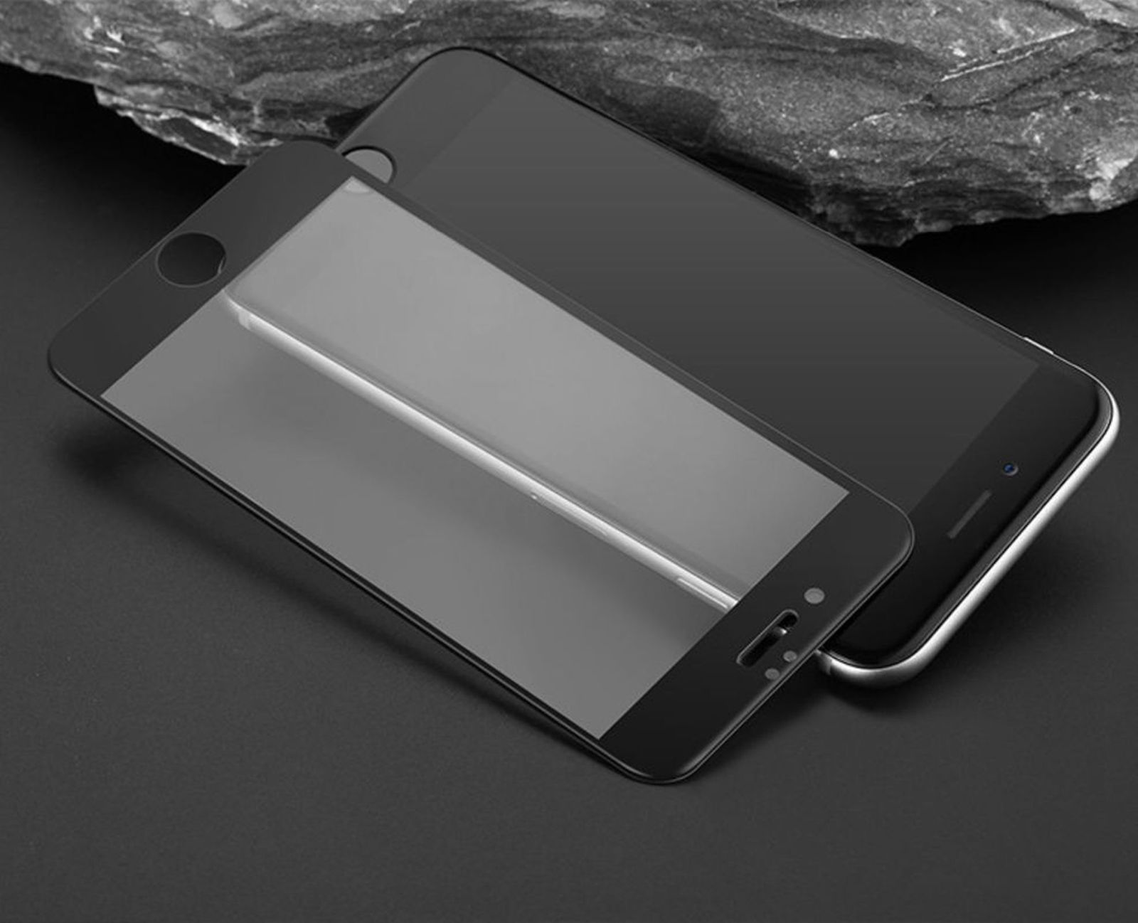 Ein Telefon mit Displayschutz oben auf einem anderen Telefon auf dunkler Oberfläche.