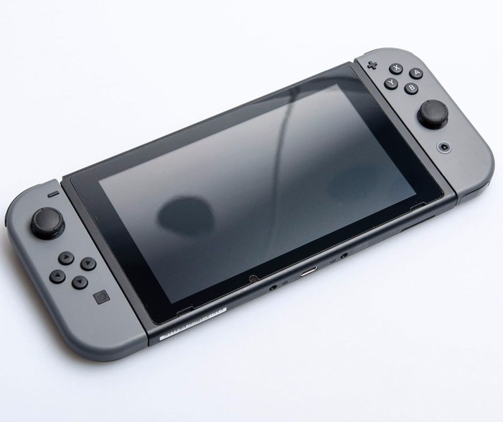 Eine graue Nintendo Switch Konsole auf weißem Untergrund. Zwei Controller sind befestigt.