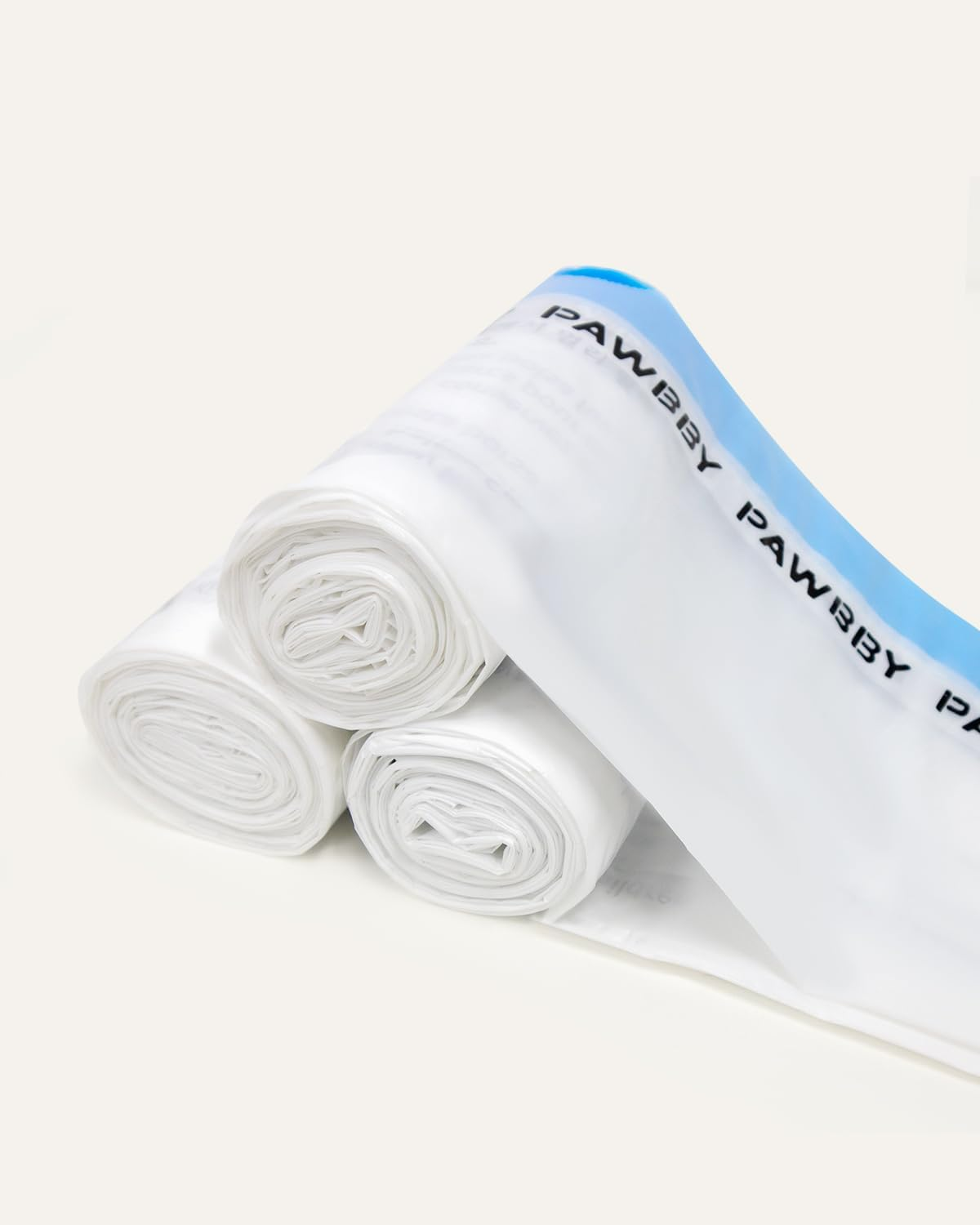 Drei Rollen weißer Plastiktüten mit blau beschrifteter Seite liegen auf einer weißen Oberfläche.