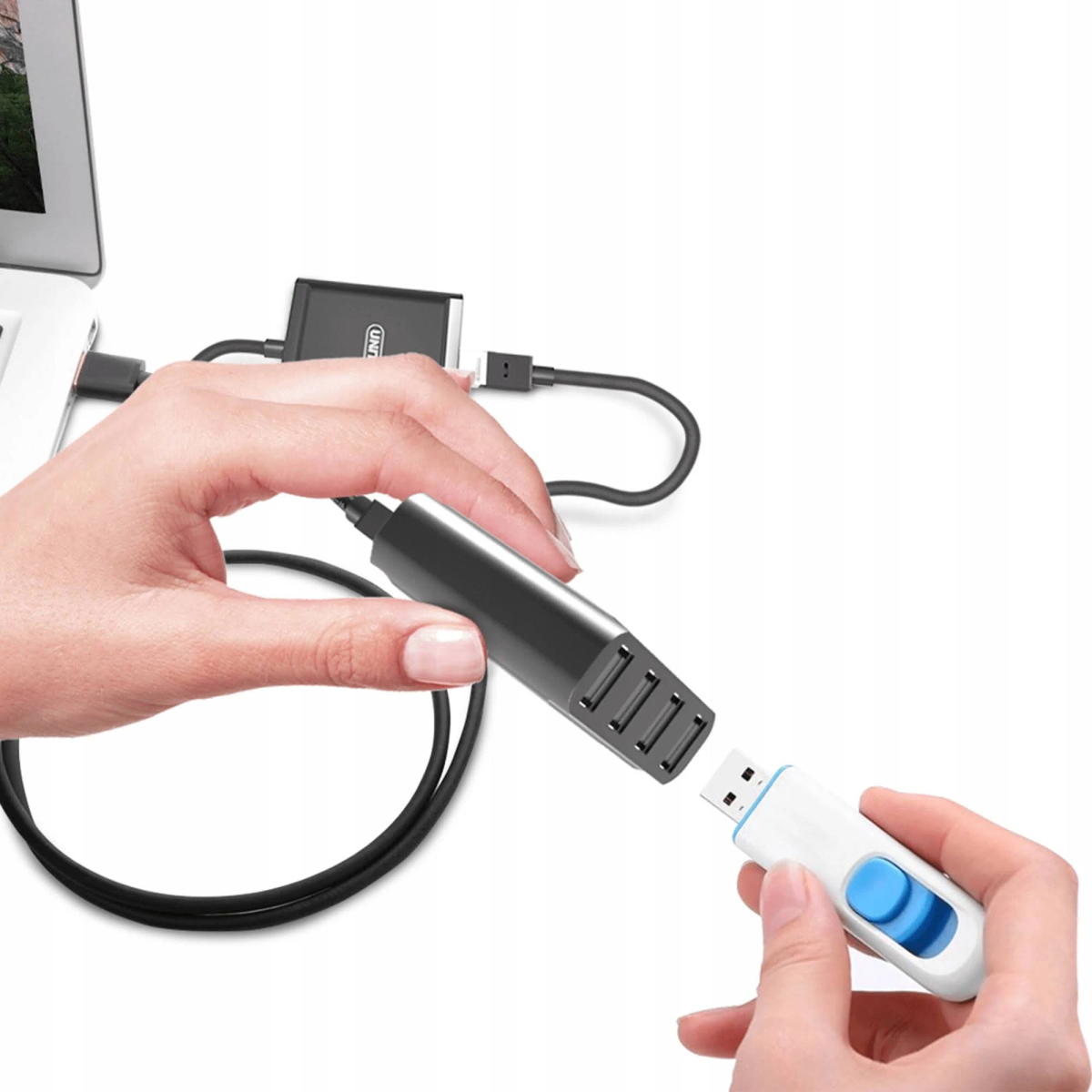 Una mano collega un adattatore USB-C nero a un'unità USB bianca. Un altro cavo a un laptop.