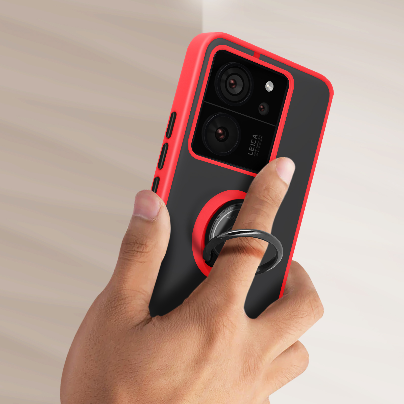 Smartphone in una custodia rossa e nera, tenuto da una mano con un anello di supporto.