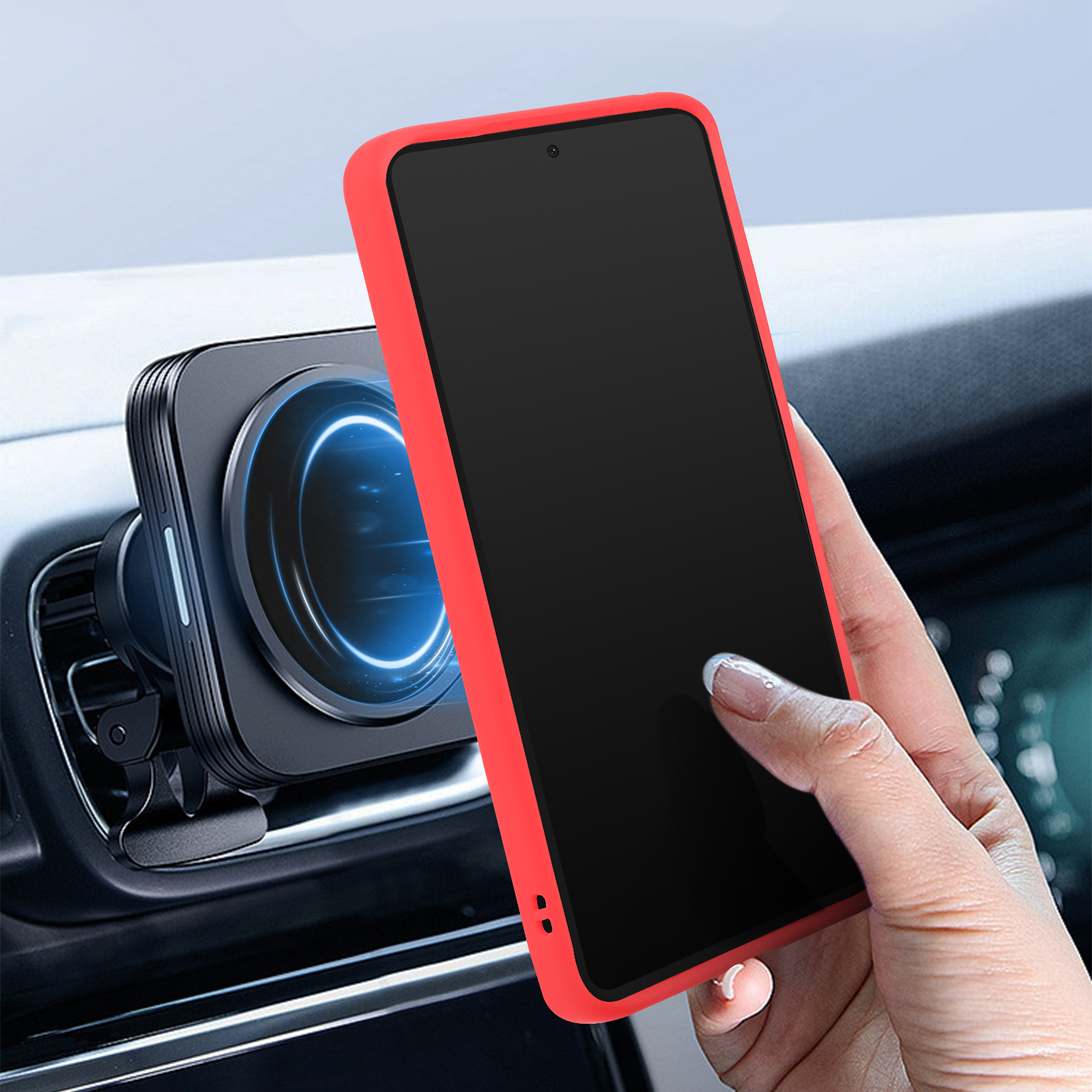Una mano che tiene un telefono rosso con una custodia rossa, accanto a un supporto per telefono nero nel cruscotto di un'auto.