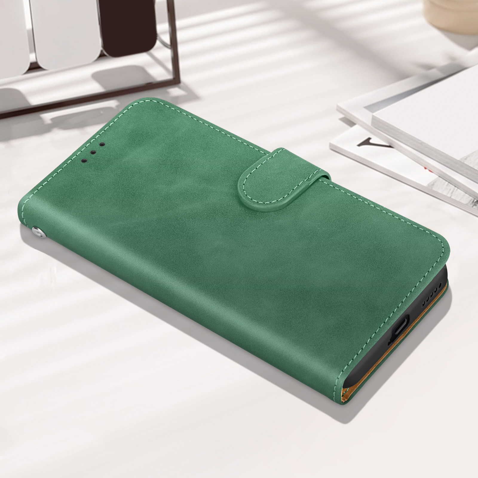 Custodia per telefono verde con chiusura a bottone, su una superficie bianca.
