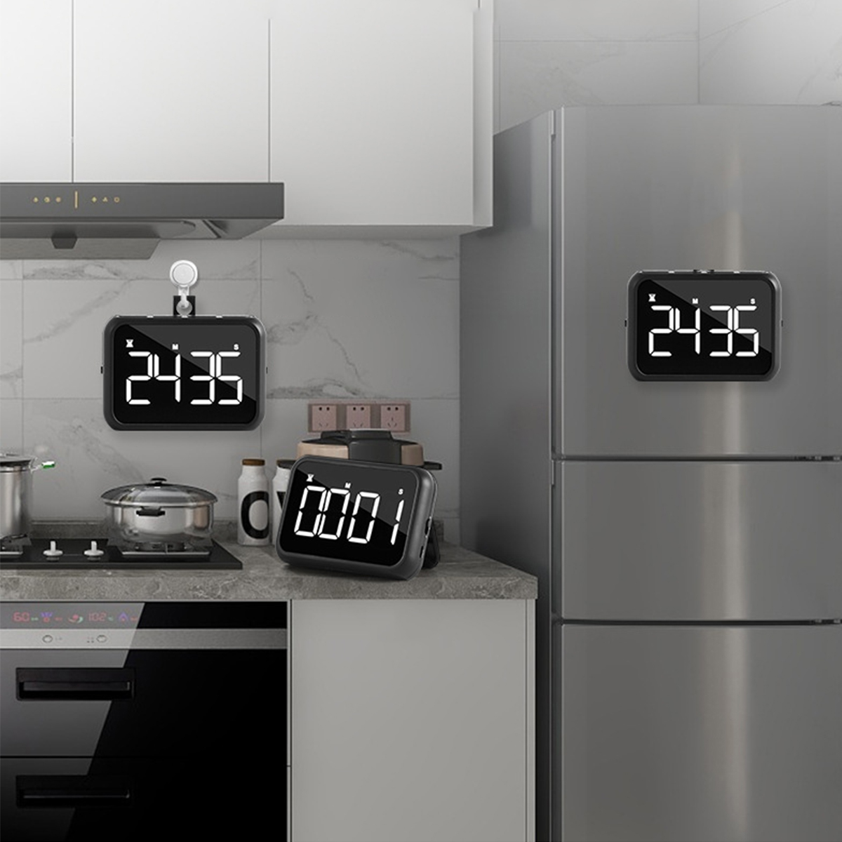 Drei schwarze digitale Küchentimer auf einer Theke und einem Kühlschrank.