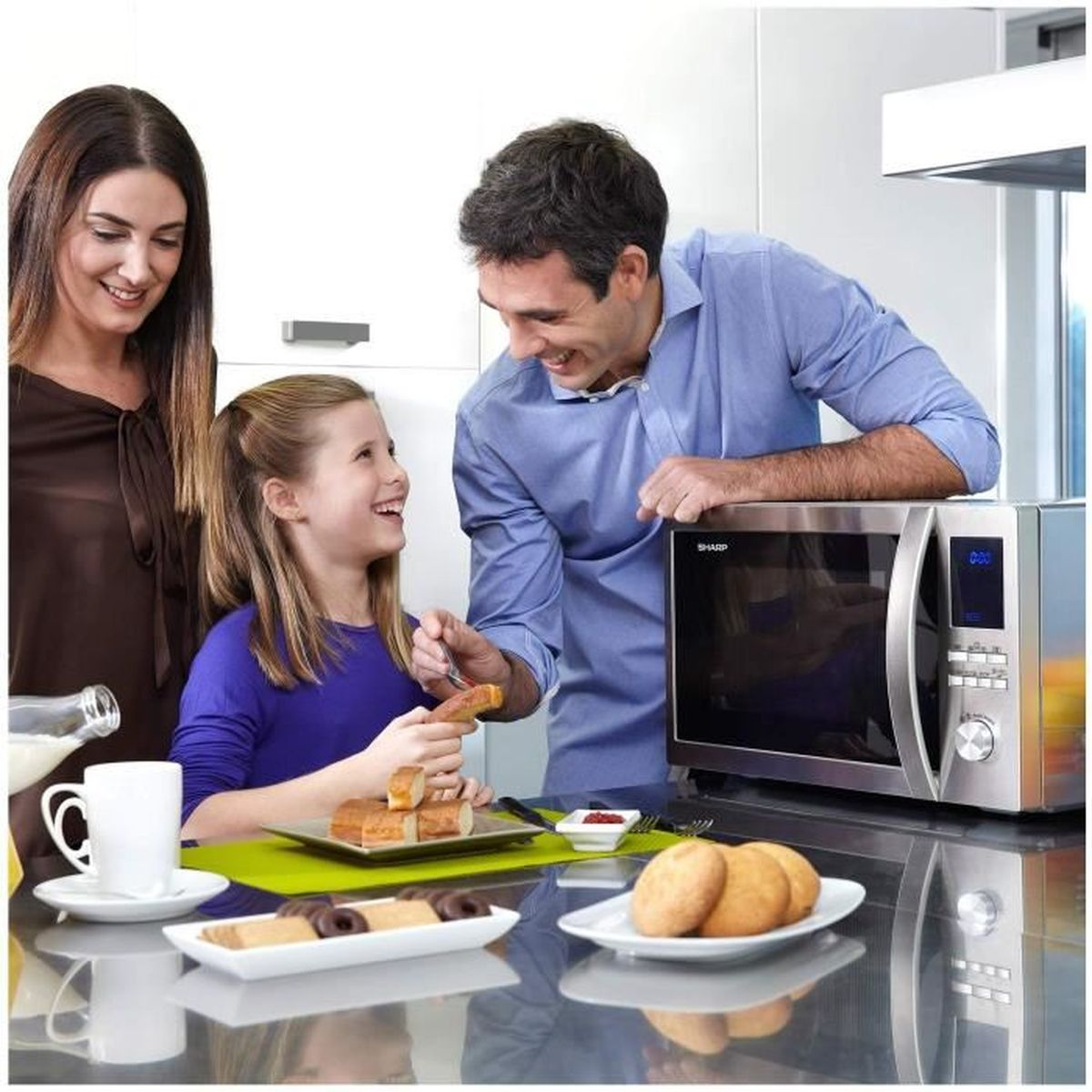Familie met een magnetron. Ouders en een kind kijken naar de magnetron.