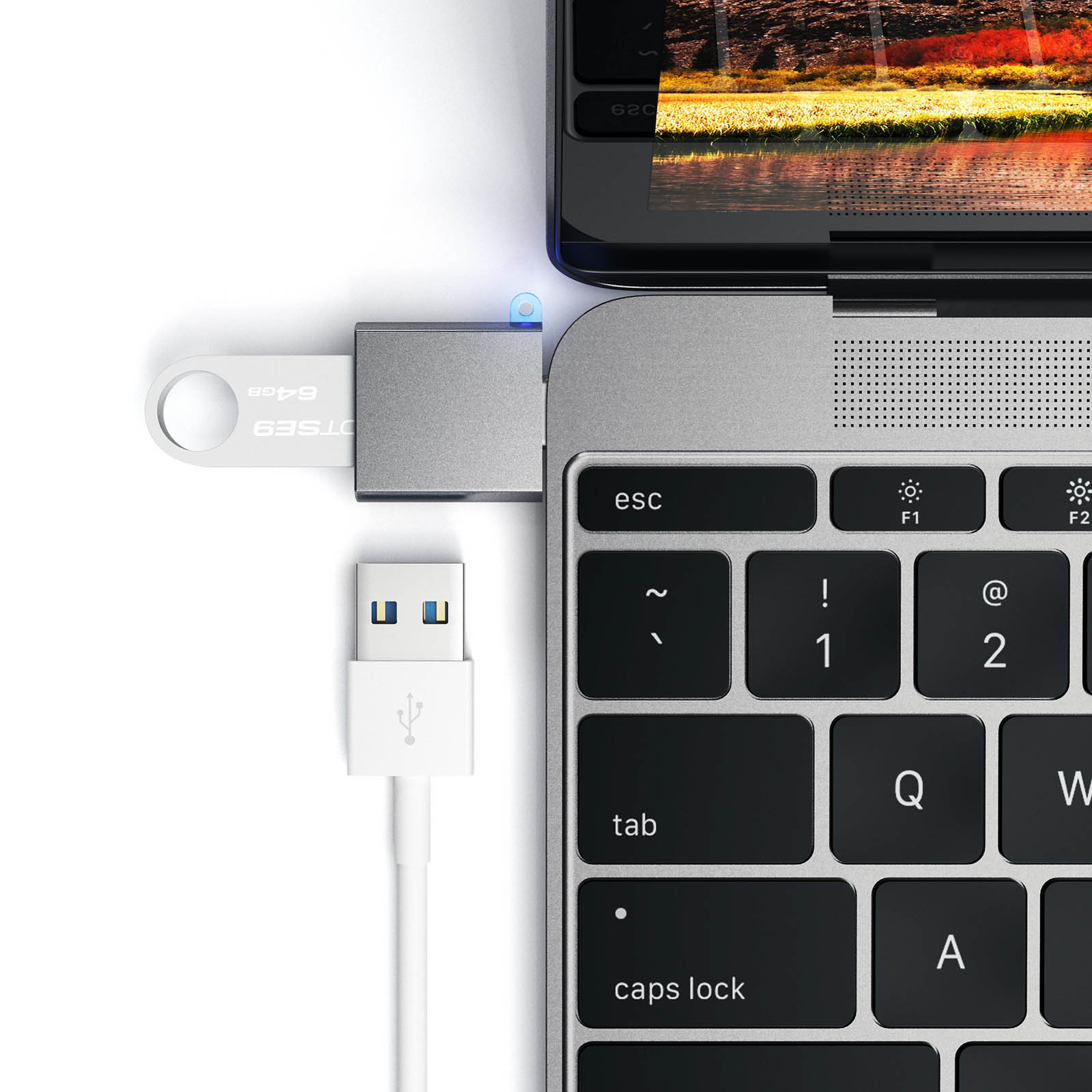 Srebrny pendrive podłączony do laptopa. Podłączony biały kabel USB.