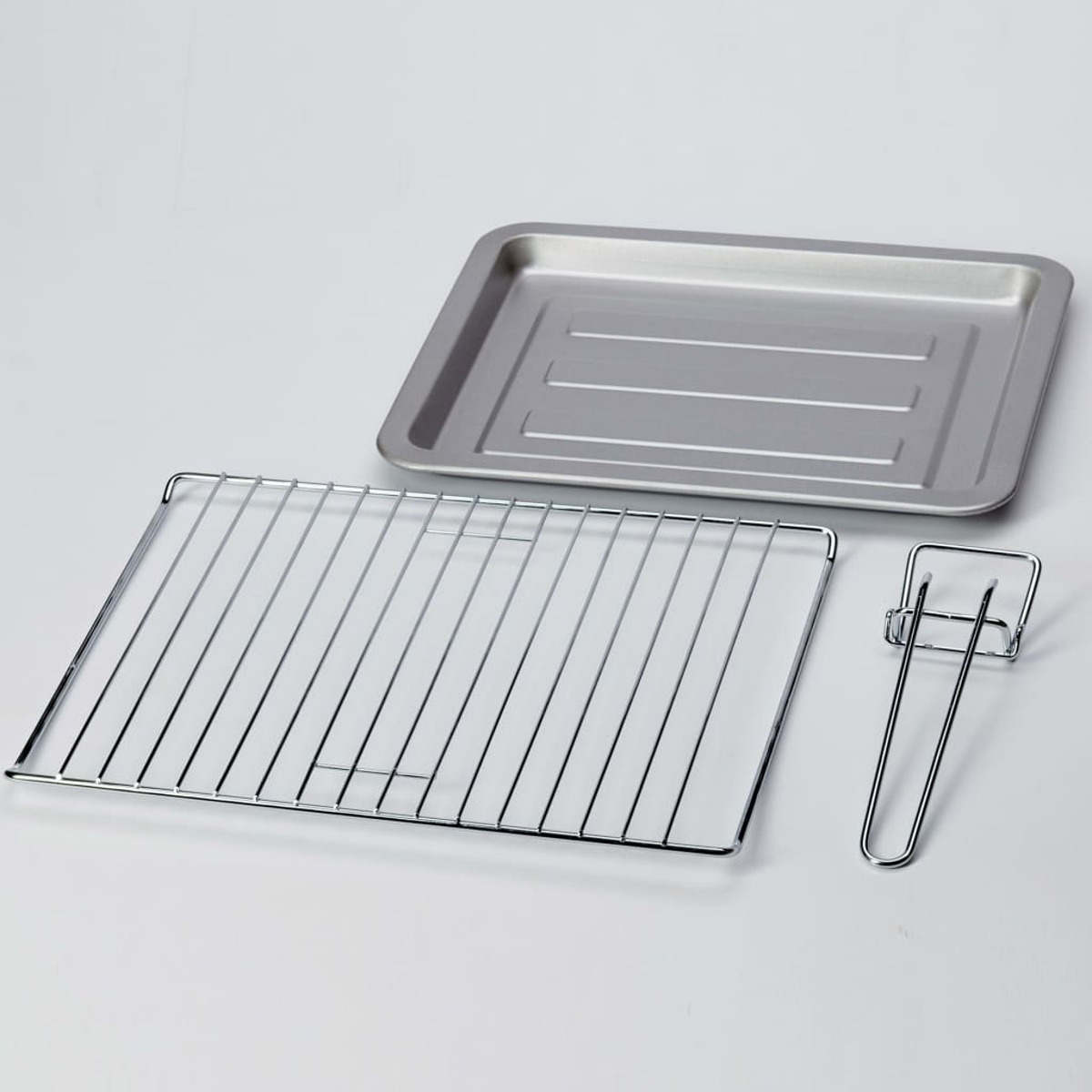 Akcesoria do piekarnika: blacha do pieczenia, ruszt i uchwyt, wszystko srebrne.