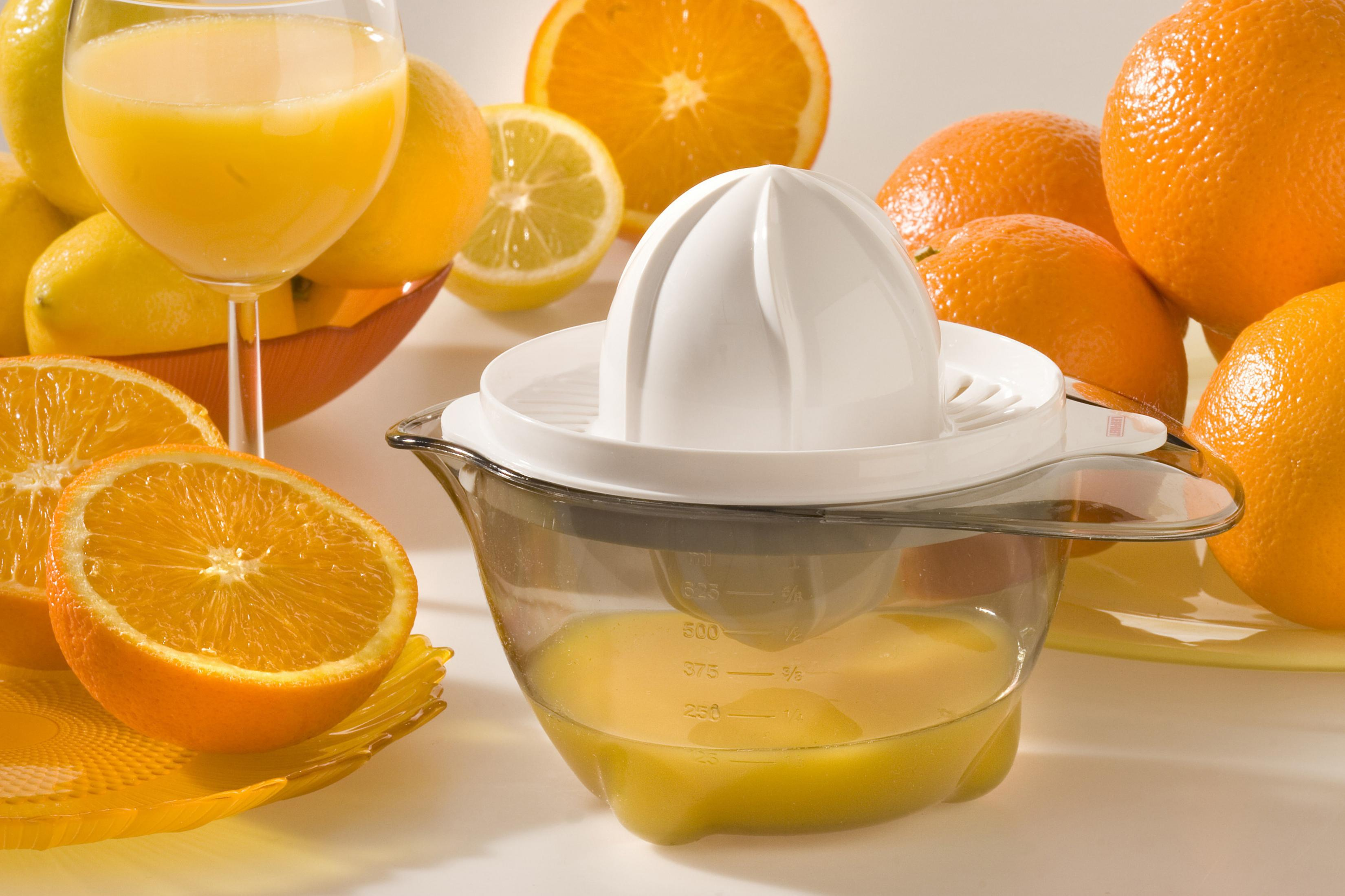 Saft und Zitrusfrüchte, Entsafter im Vordergrund, Orangen und Zitronen herum.