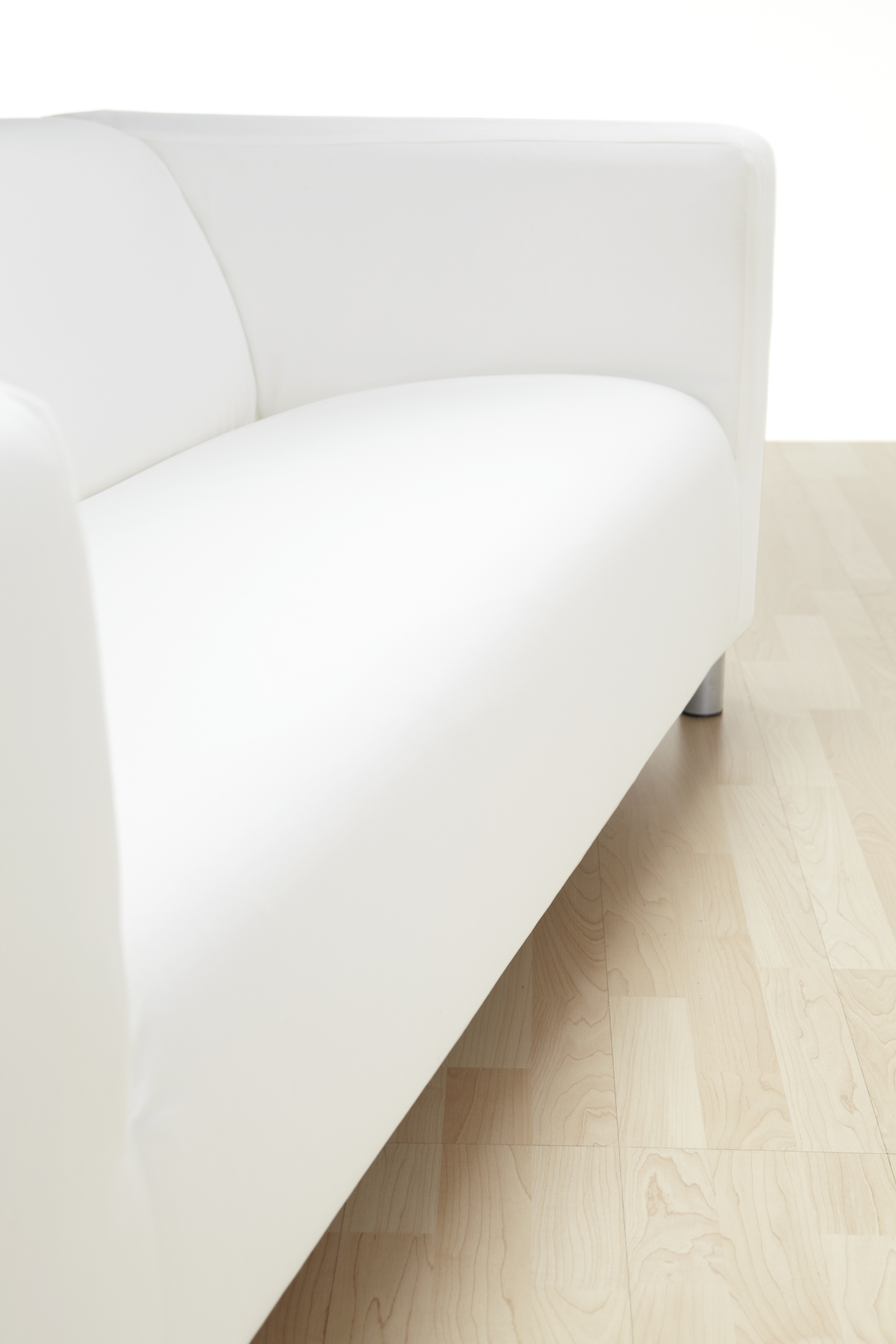 Nahaufnahme eines weißen, modernen Sofas auf hellem Holzboden. Weißer Hintergrund.
