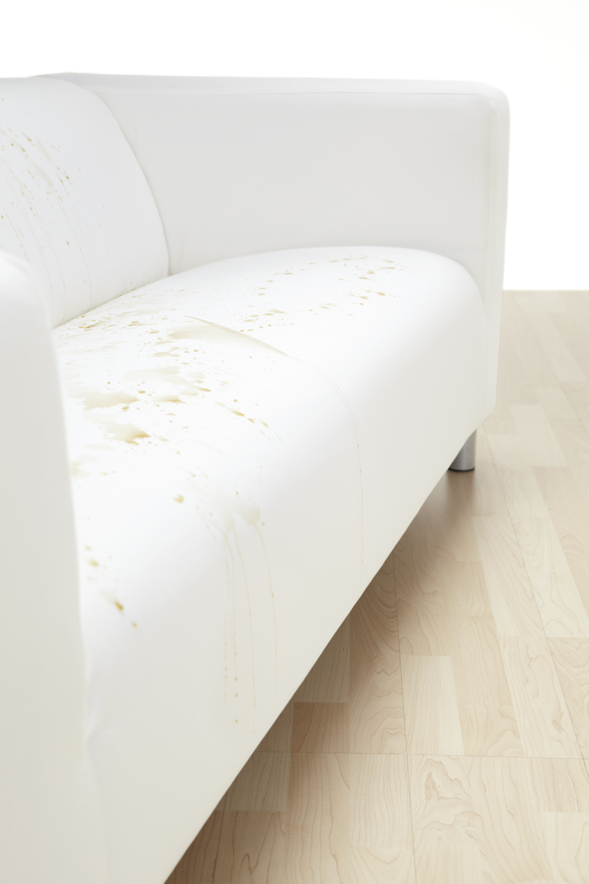 Weißes Sofa mit Flecken. Heller Holzboden und weißer Hintergrund.
