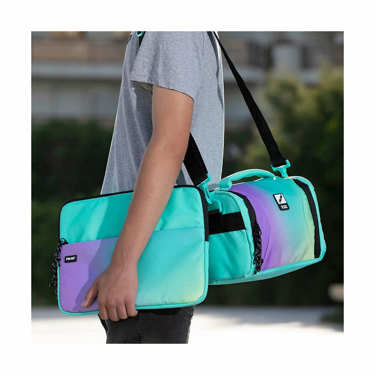 Person trägt ein farbenfrohes Taschenset. Das Set enthält eine Laptoptasche und eine Reisetasche.