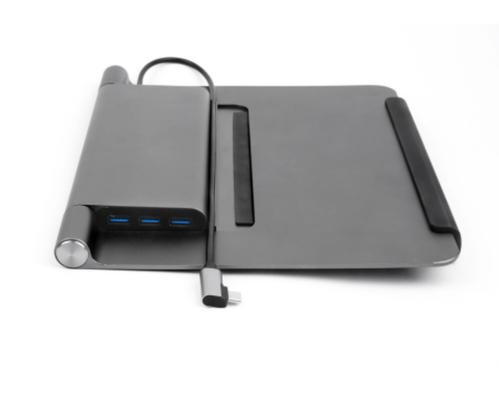 Un dock per laptop grigio con porte e un cavo USB-C è posizionato su una superficie bianca.