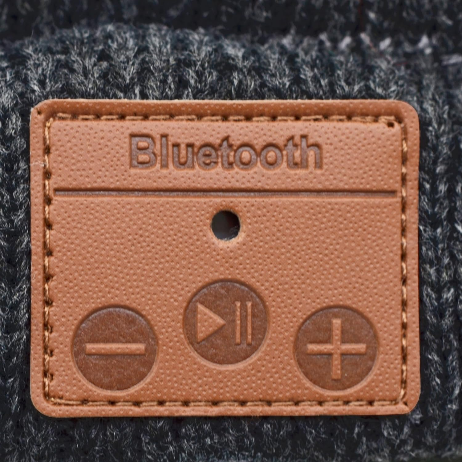 Primo piano di una toppa marrone con la scritta 'Bluetooth' e simboli di controllo.
