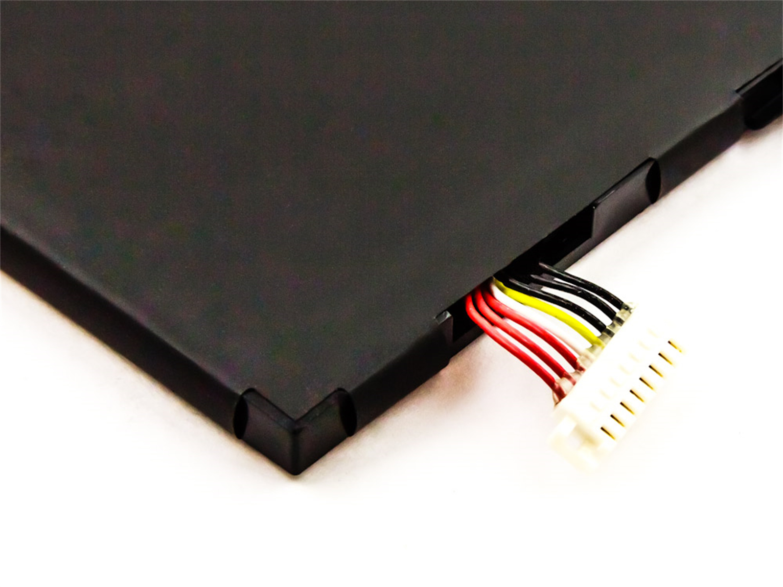 Schwarzer Laptop-Akku mit mehrfarbigen Drähten und einem weißen Stecker auf weißer Oberfläche.