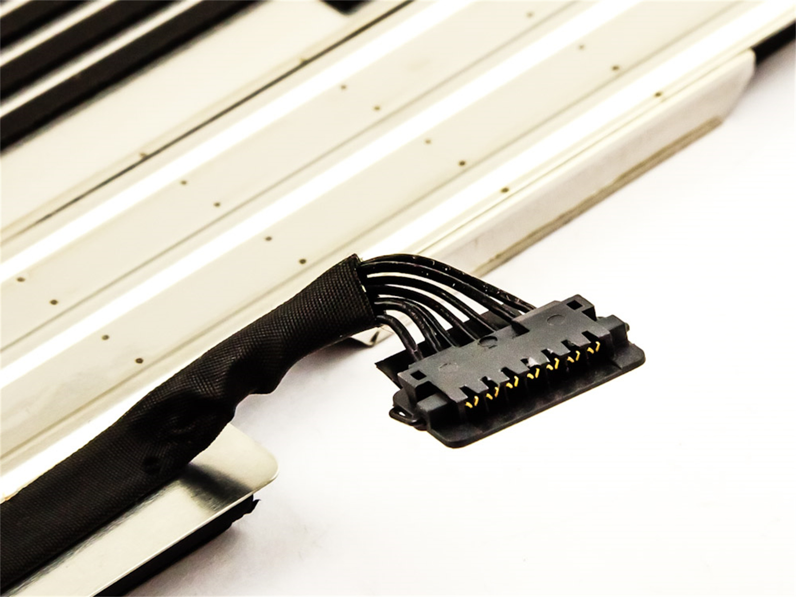 Nahaufnahme eines Steckers mit schwarzem Kabel und einigen metallischen Komponenten auf Weiß.