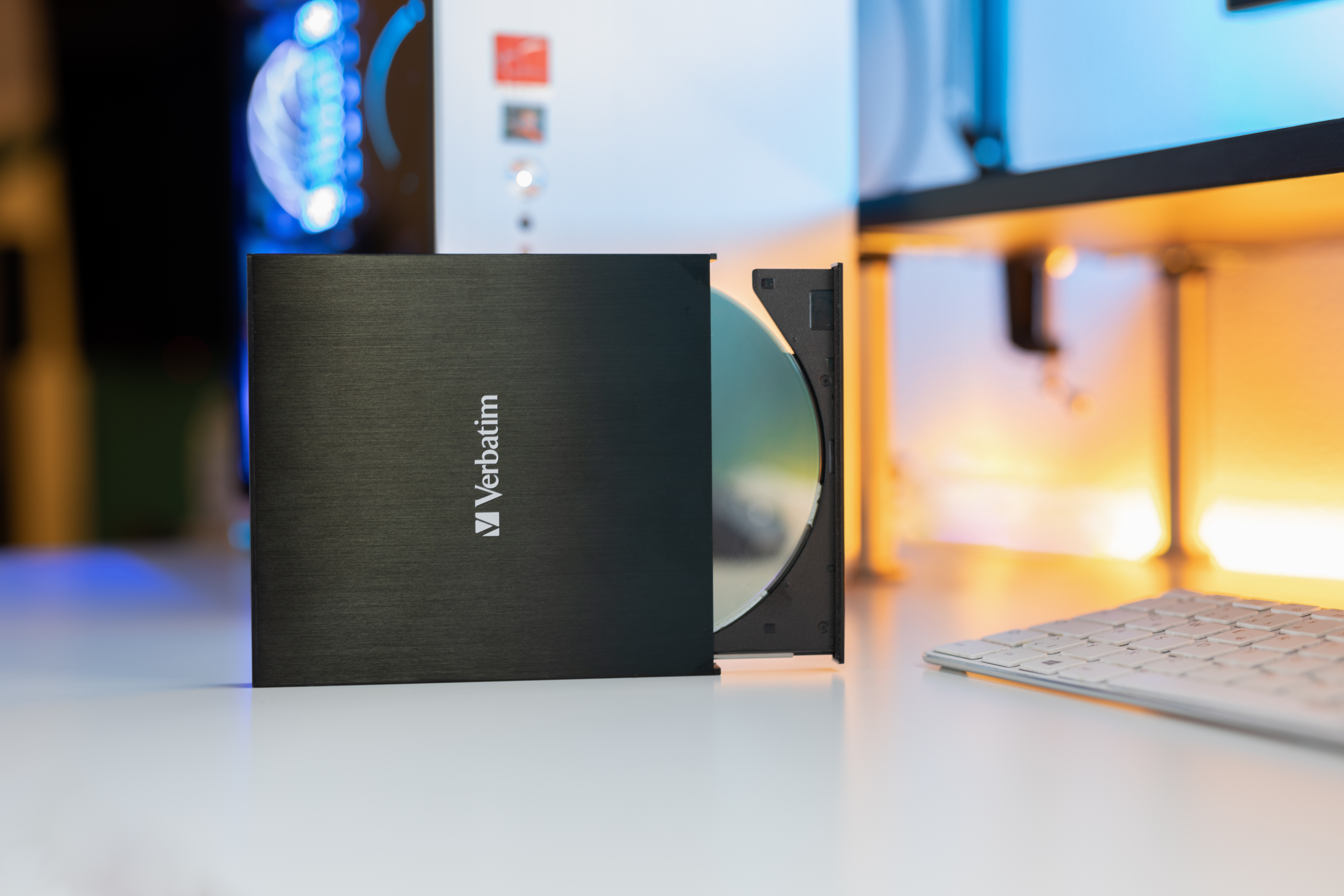 Czarny zewnętrzny napęd CD/DVD z płytą w środku. Białe tło, ustawienie biurka.