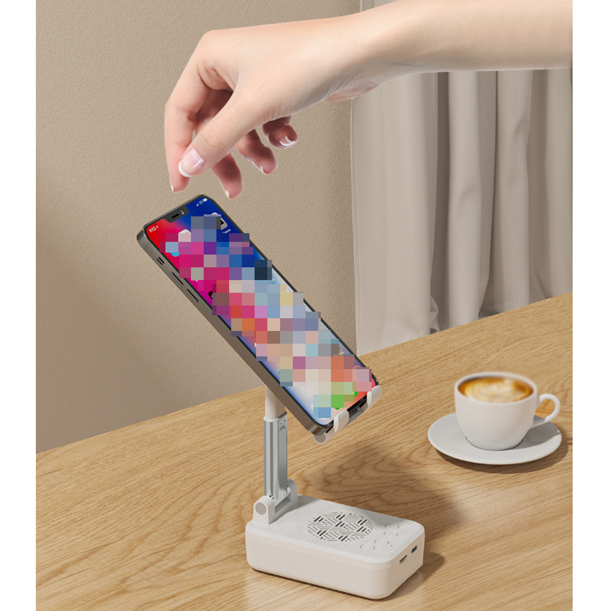 Telefon auf einem Ständer, eine Hand justiert ihn. Daneben eine Kaffeetasse auf Holz.