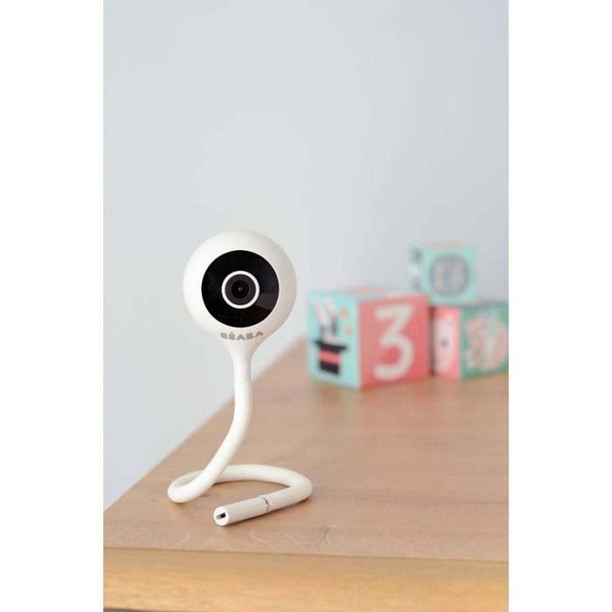 Babyphone auf einem Holztisch. Weiße, gebogene Kamera mit schwarzem Objektiv.