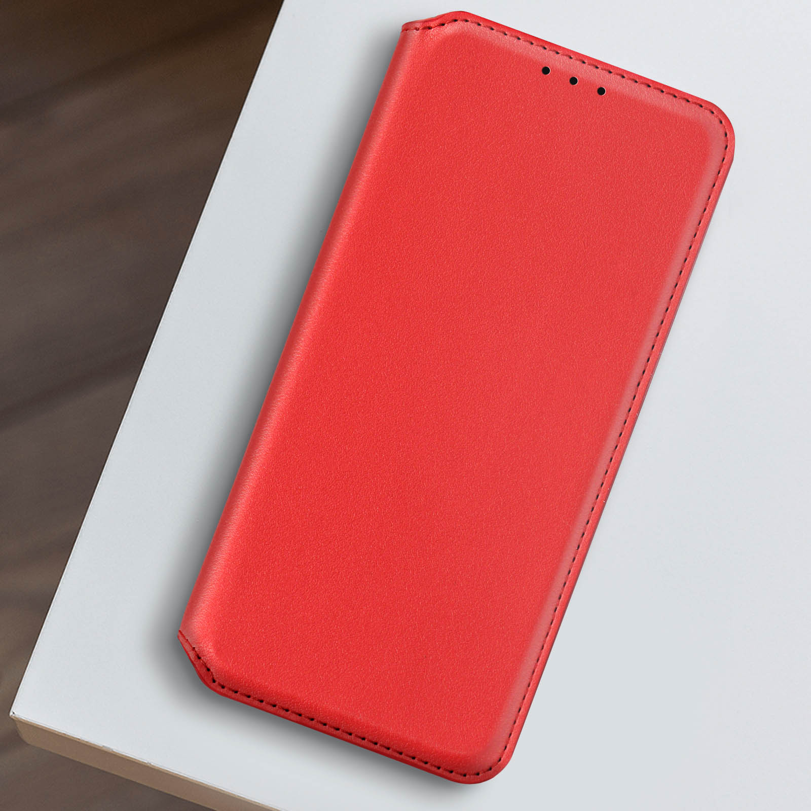 Custodia per telefono rossa su una superficie bianca, vista dall'alto, design semplice.