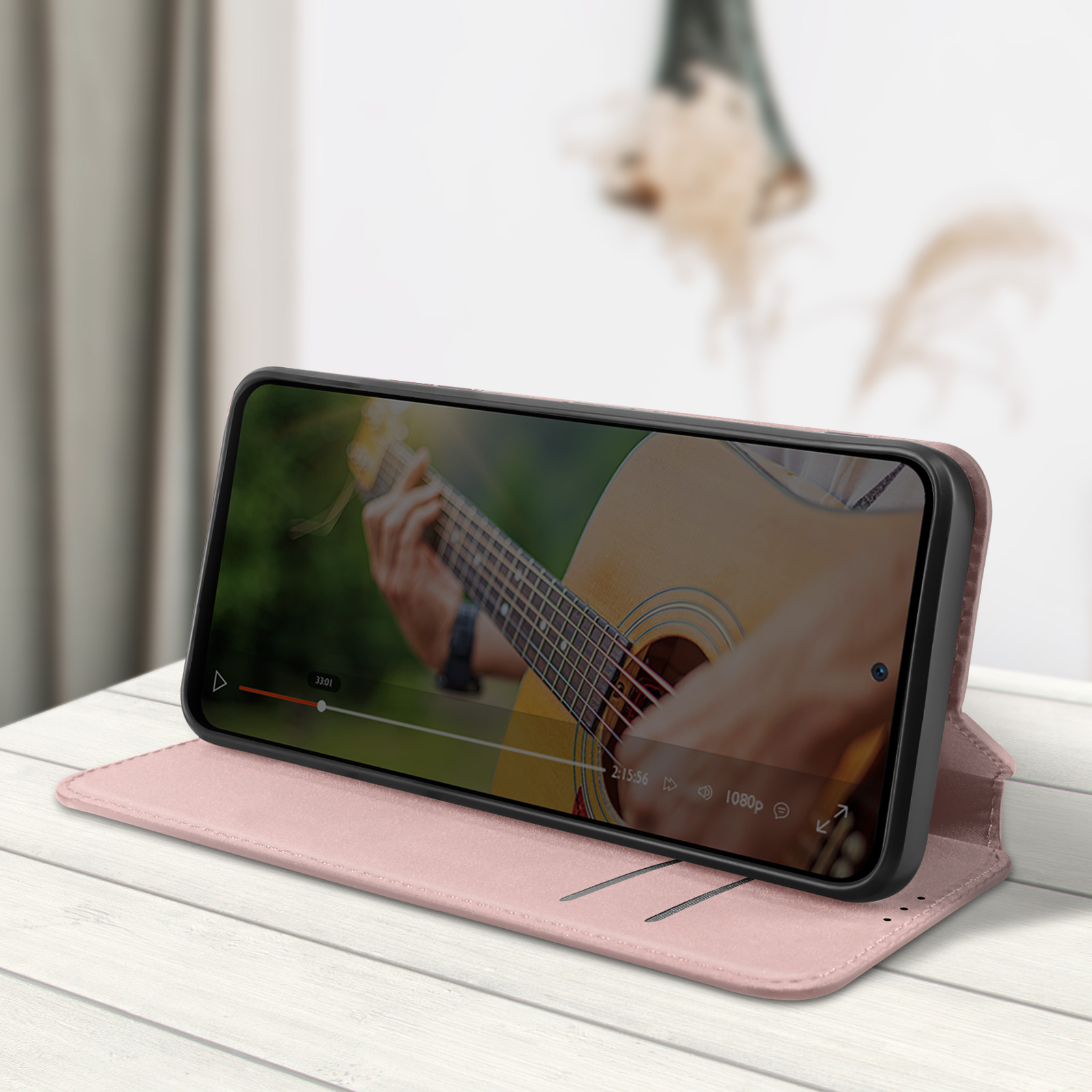 Un telefono con una custodia rosa mostra un video di qualcuno che suona la chitarra.