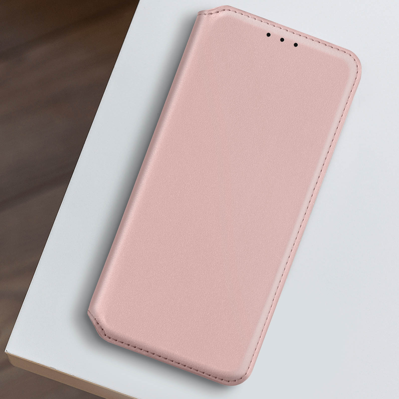 Custodia per telefono rosa con superficie liscia e piccola apertura per la fotocamera, su una superficie bianca.