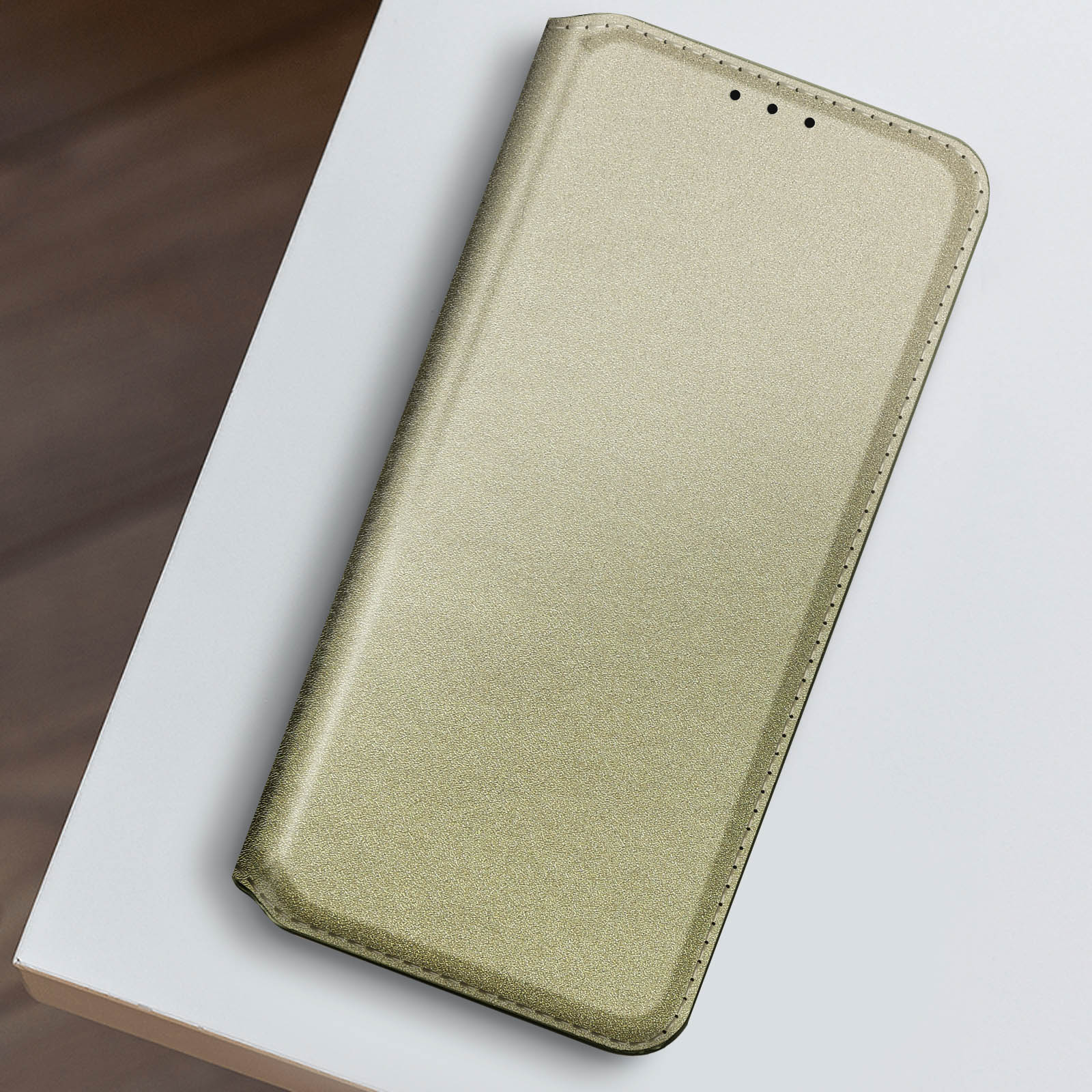 Una custodia per telefono color oro, aperta e piatta. La custodia ha una superficie strutturata.