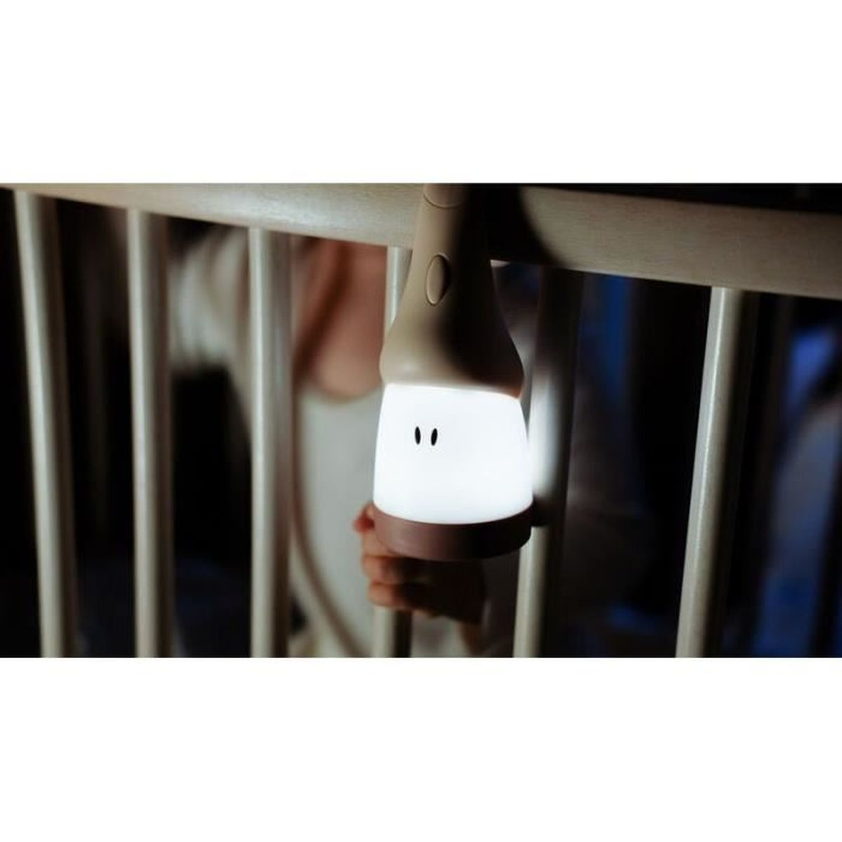 Ein Nachtlicht hängt am Kinderbett und beleuchtet ein lächelndes Gesicht.